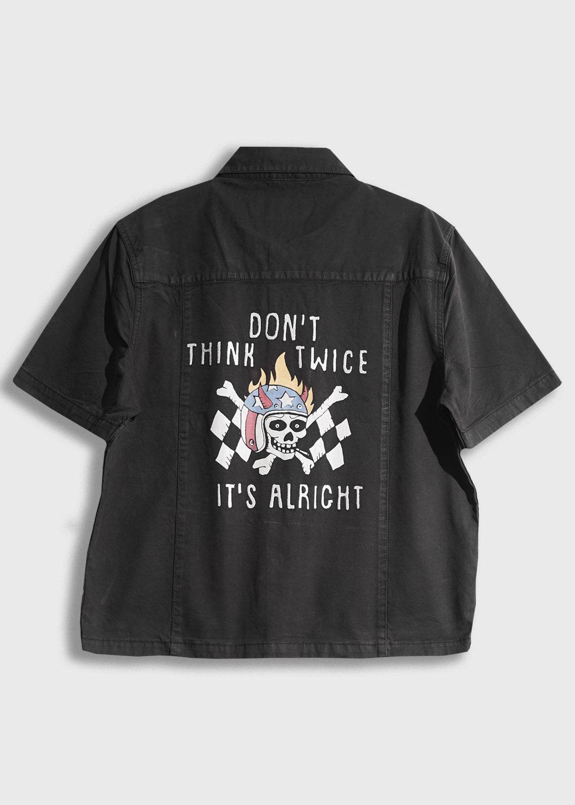 Black shirt with a skull and checkered flags, text reads "Don't think twice, it's alright" in white. Casual, edgy design.