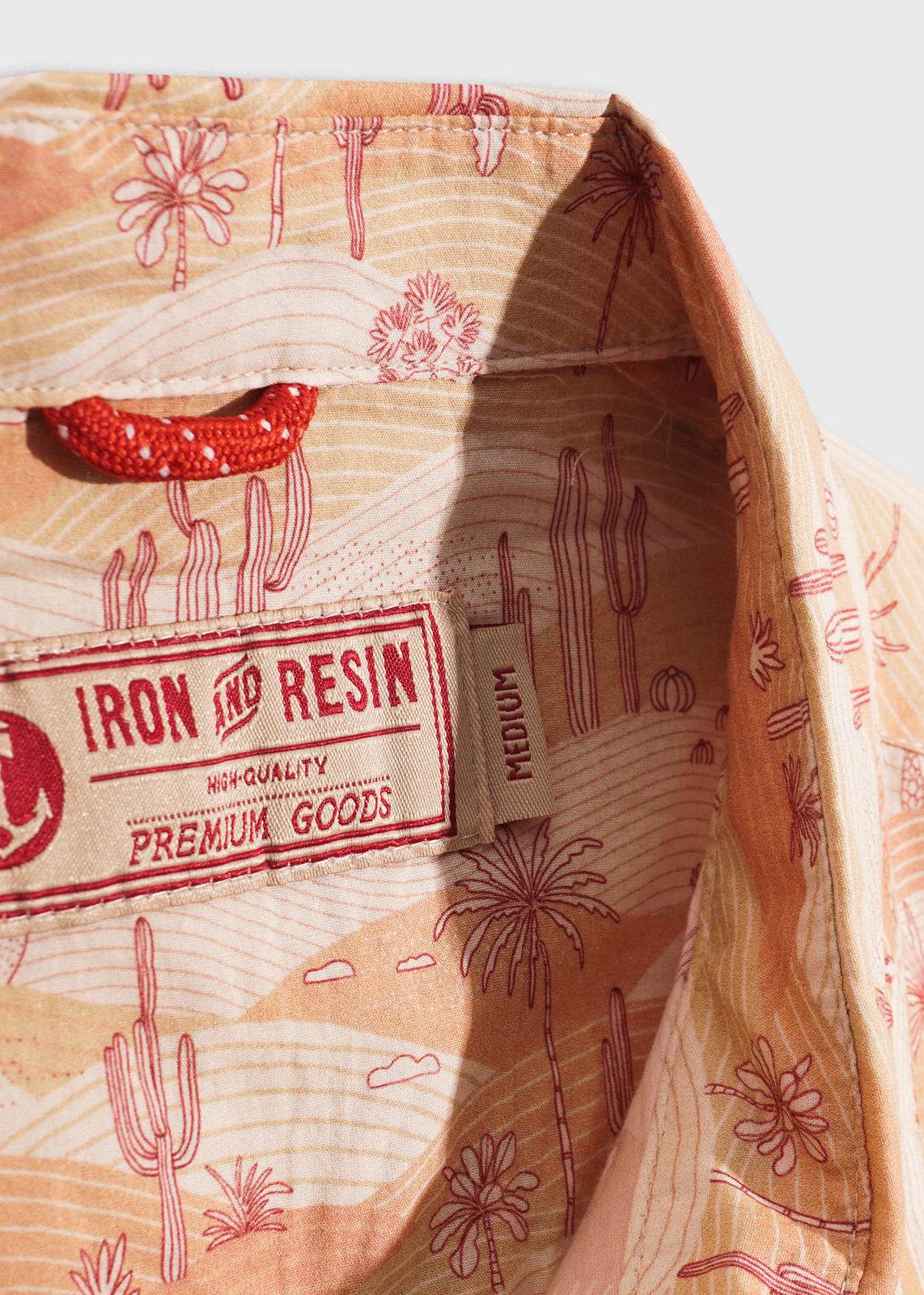 Shirt collar with desert-themed print, featuring cacti and palm trees. Label reads "Iron and Resin, High-Quality Premium Goods."
