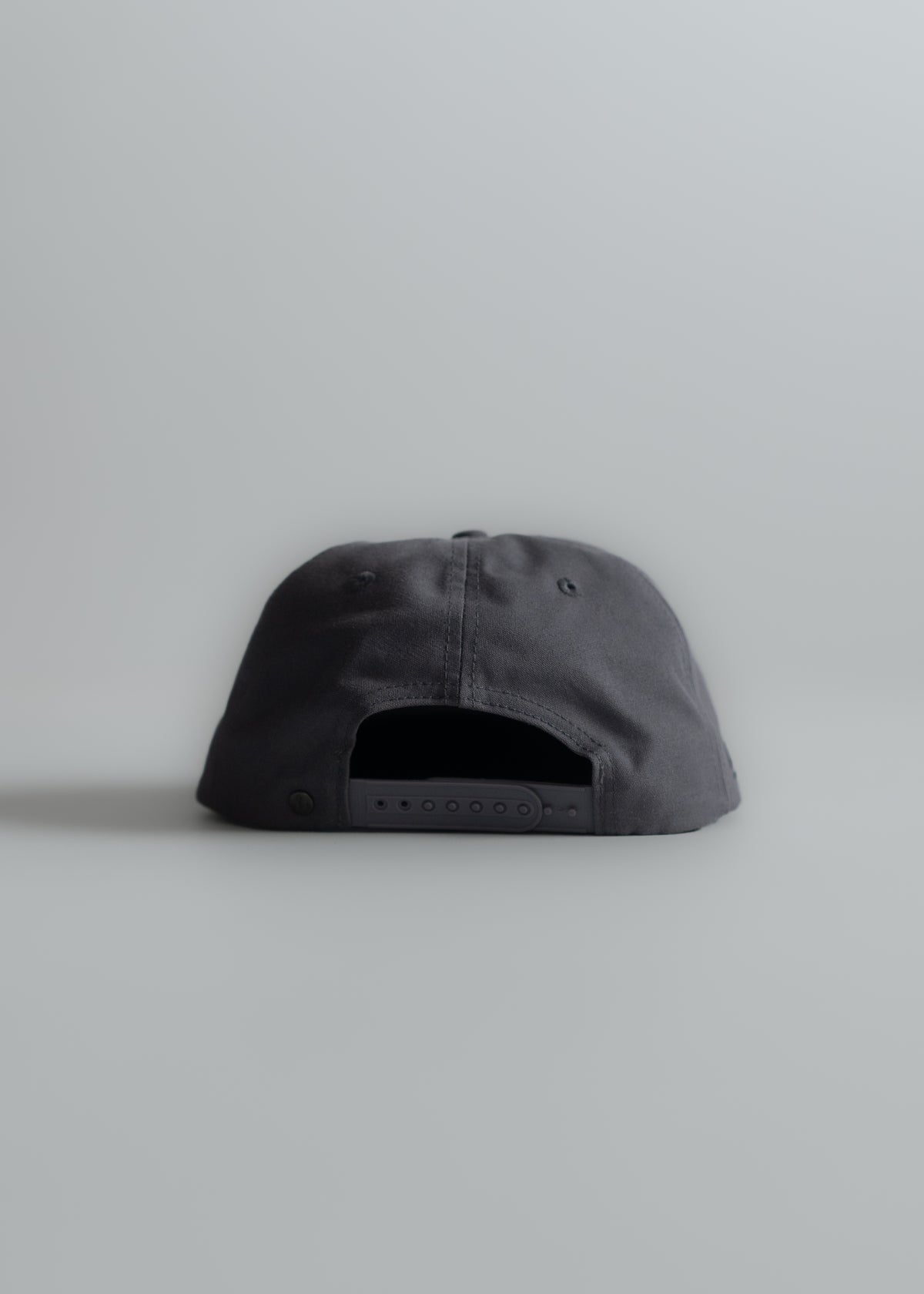 Back view of a black baseball cap with an adjustable strap, set against a plain gray background.
