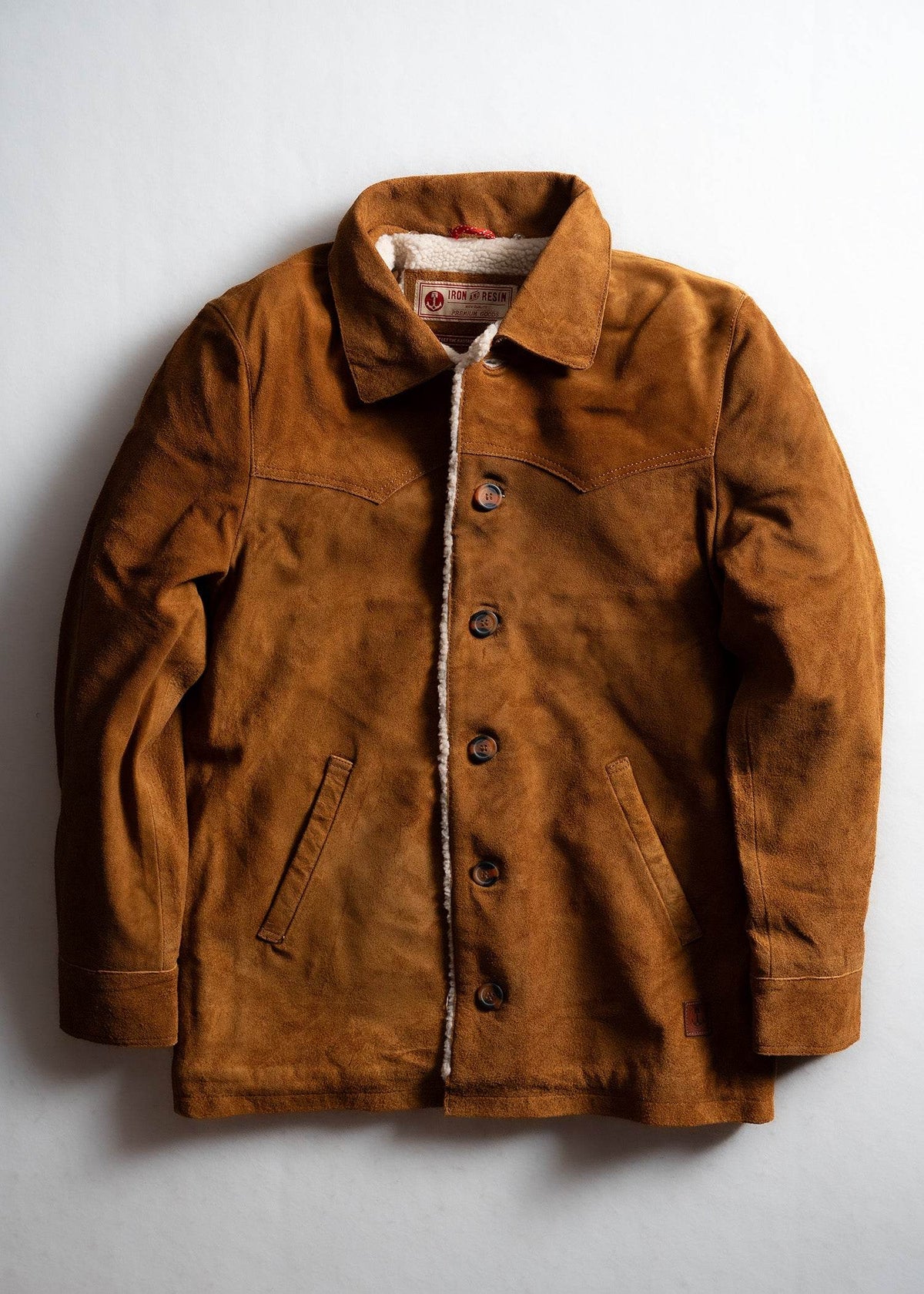 Brown suede jacket with buttons and pockets, lined with white fleece, displayed on a white background.