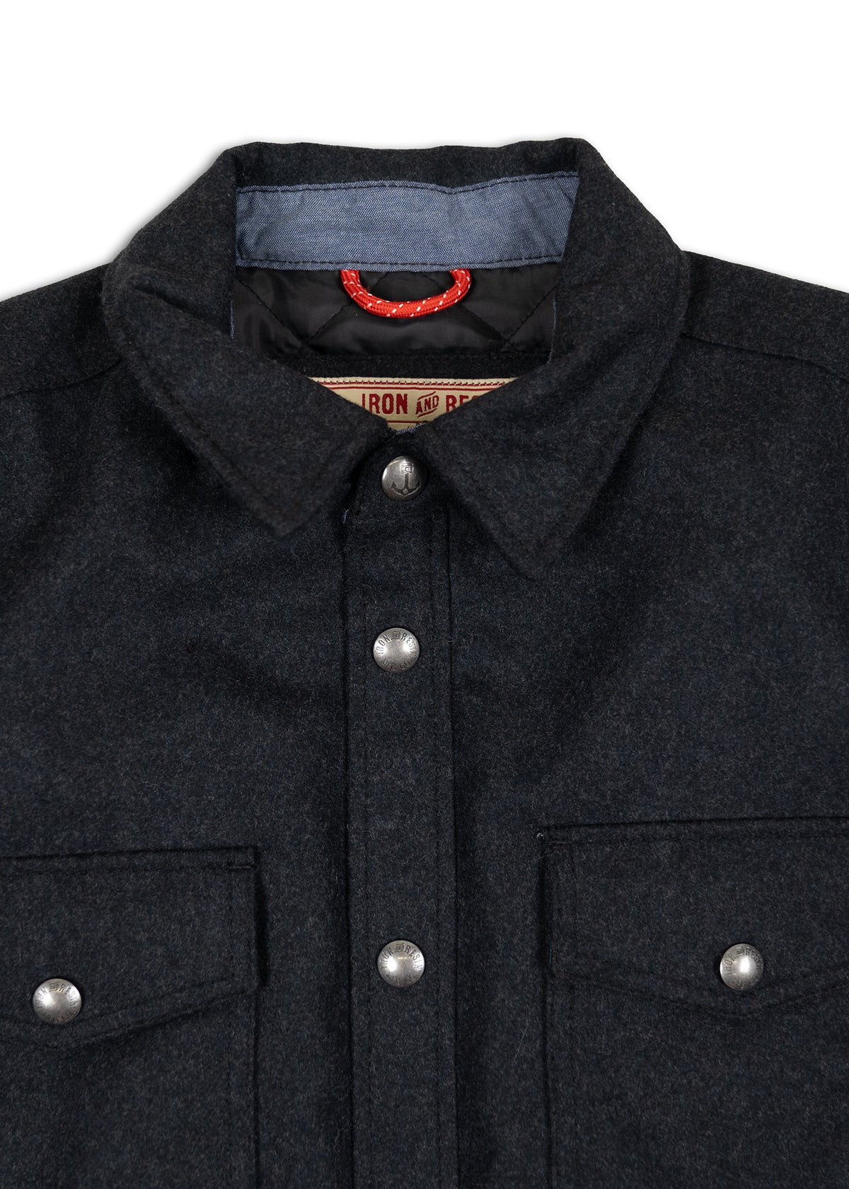 Dark wool shirt with metal buttons, two chest pockets, and a red loop inside the collar. Label reads "Iron and Resin."