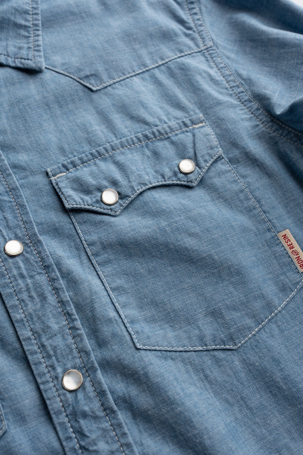 Close up of snap buttons on chambray shirt, highlighting chest pocket and hardware detail and front closure