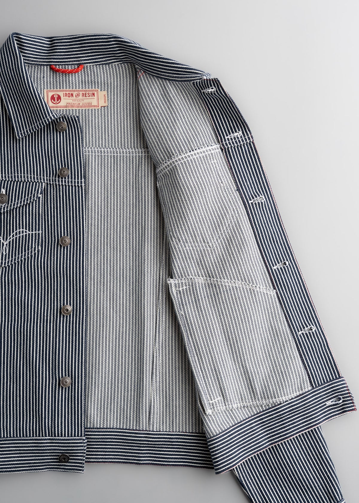 Blue and white striped jacket with open front, revealing label "Iron and Resin" inside. Button details visible on the left side.