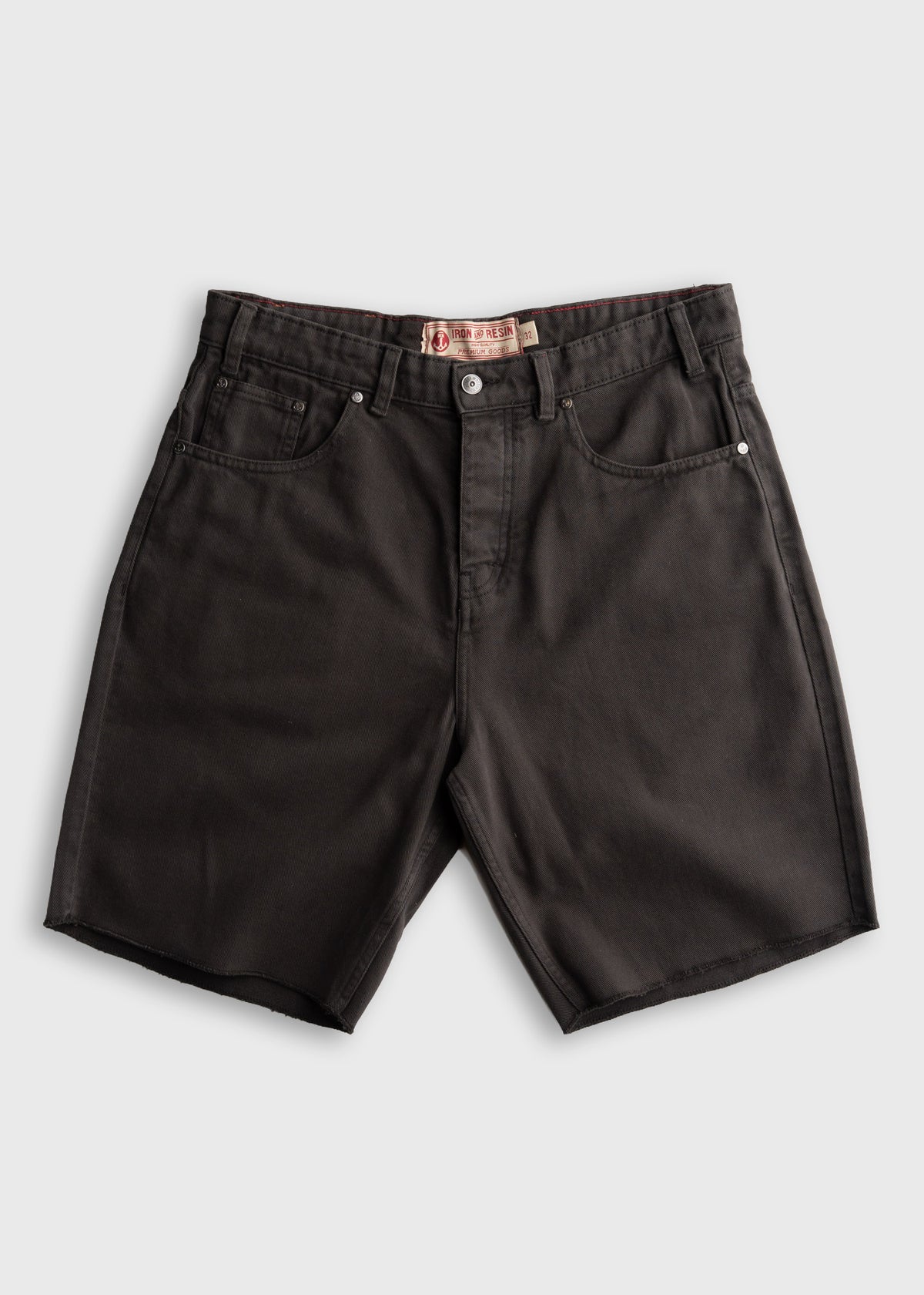 Black denim shorts with a button fly, front pockets, and a visible "Iron & Resin" label on the waistband, laid flat on white.