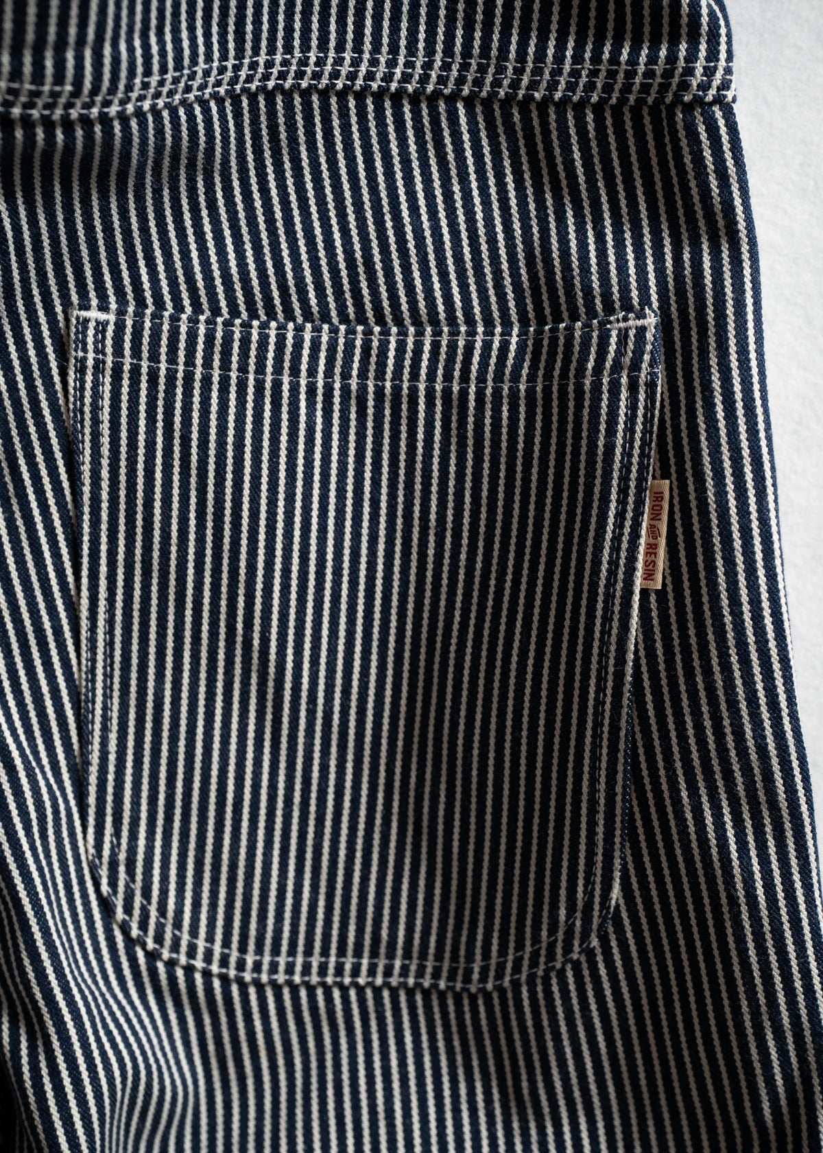 Close-up of blue and white striped fabric with a pocket, showcasing detailed stitching and texture.