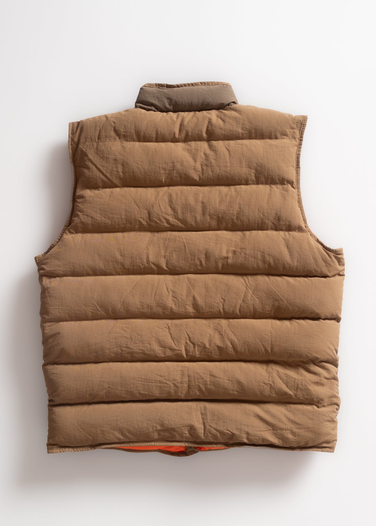 Brown puffer vest with a high collar, viewed from the back, on a white background. The vest is quilted and appears warm.