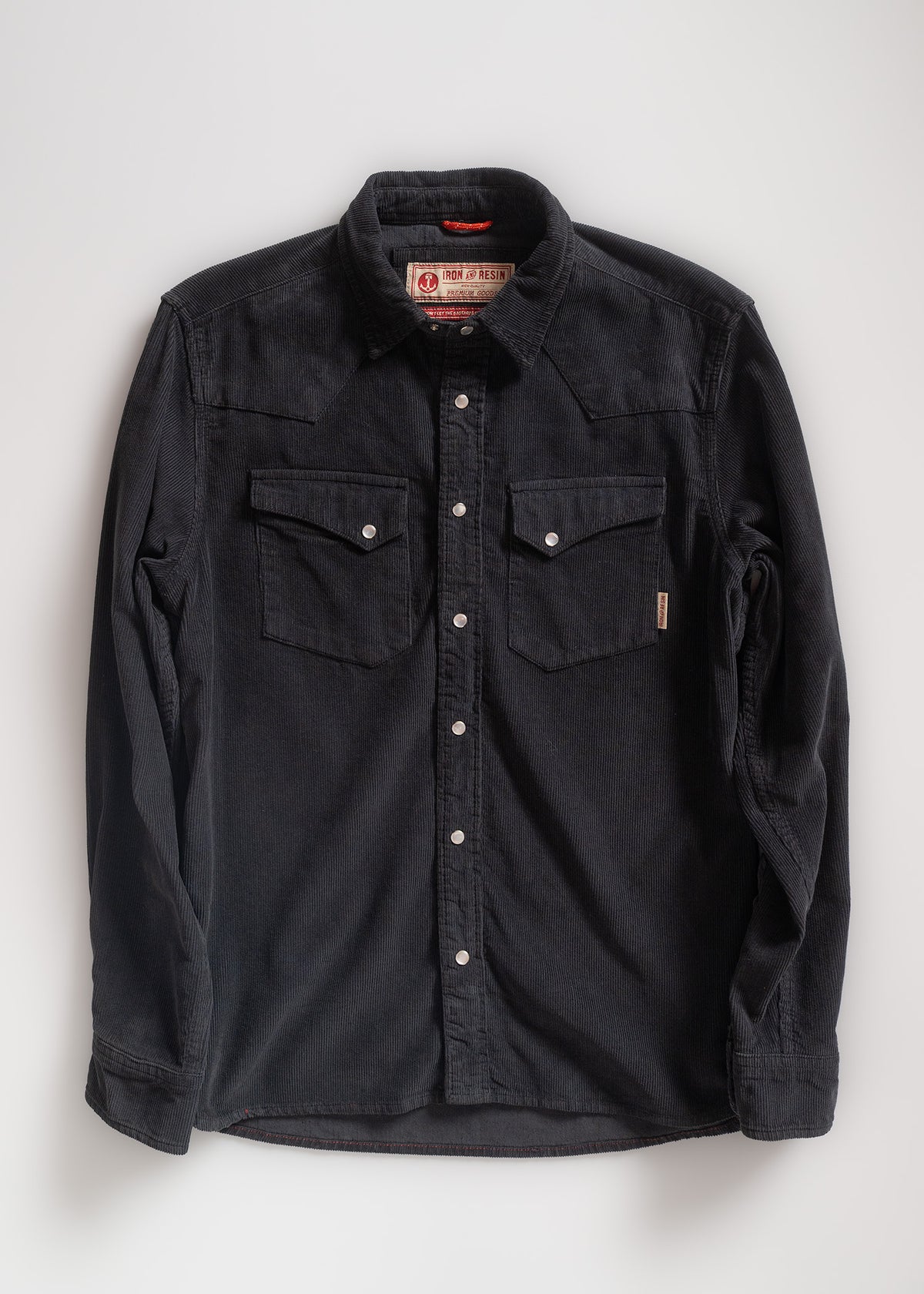 Black corduroy shirt with button-up front and two chest pockets, displayed flat on a white background.