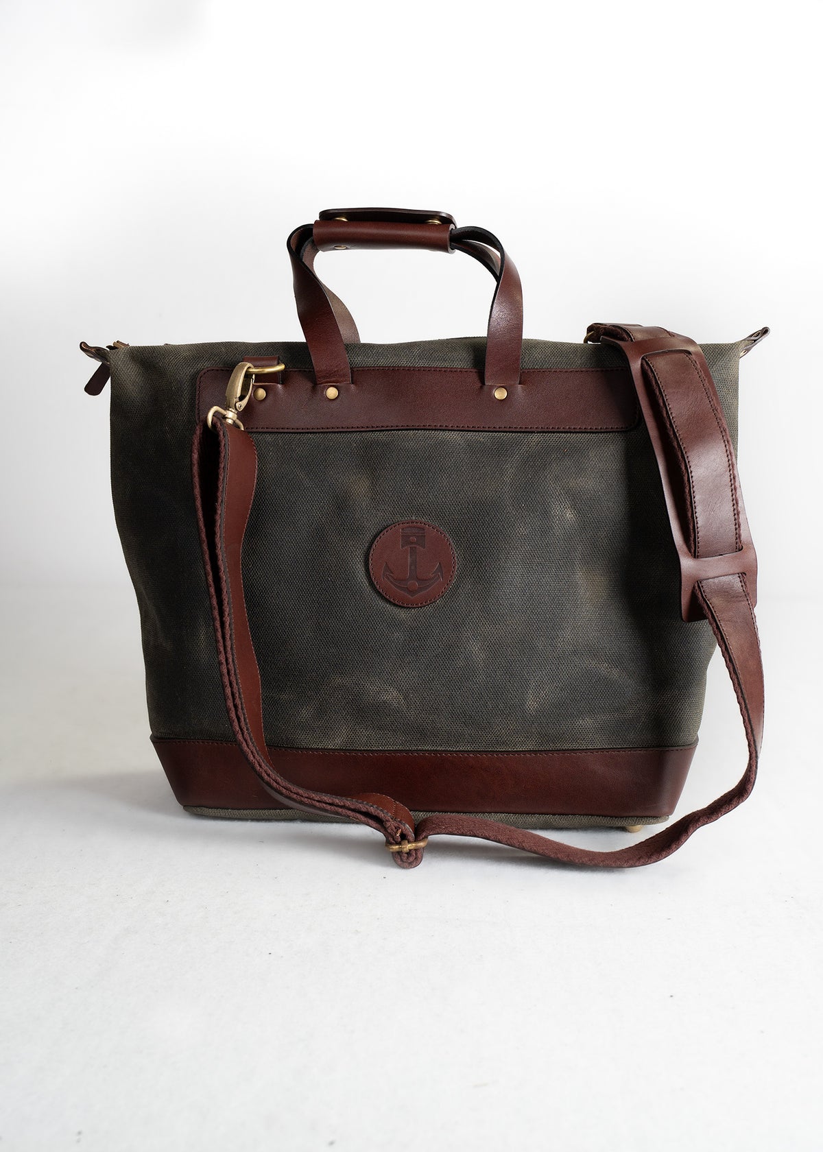 A stylish canvas tote bag with brown leather accents and an anchor logo, featuring a shoulder strap and sturdy handles.