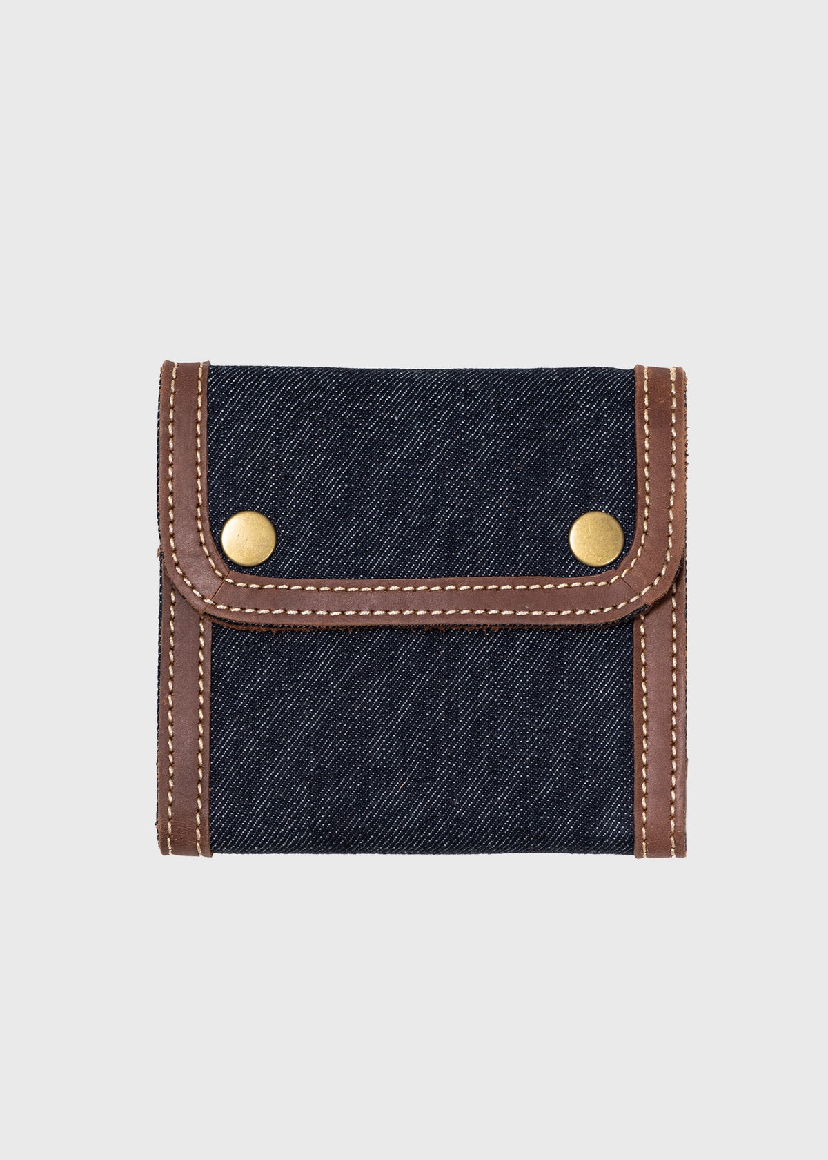 Denim wallet with brown leather trim and brass snap buttons, showcasing a stylish and compact design on a plain background.