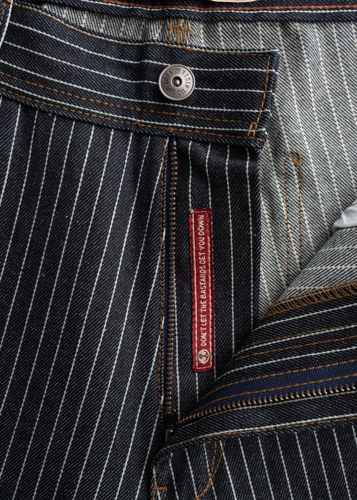 Close up of YKK zipper fly and shank button waistband, highlighting front closure and hardware detail