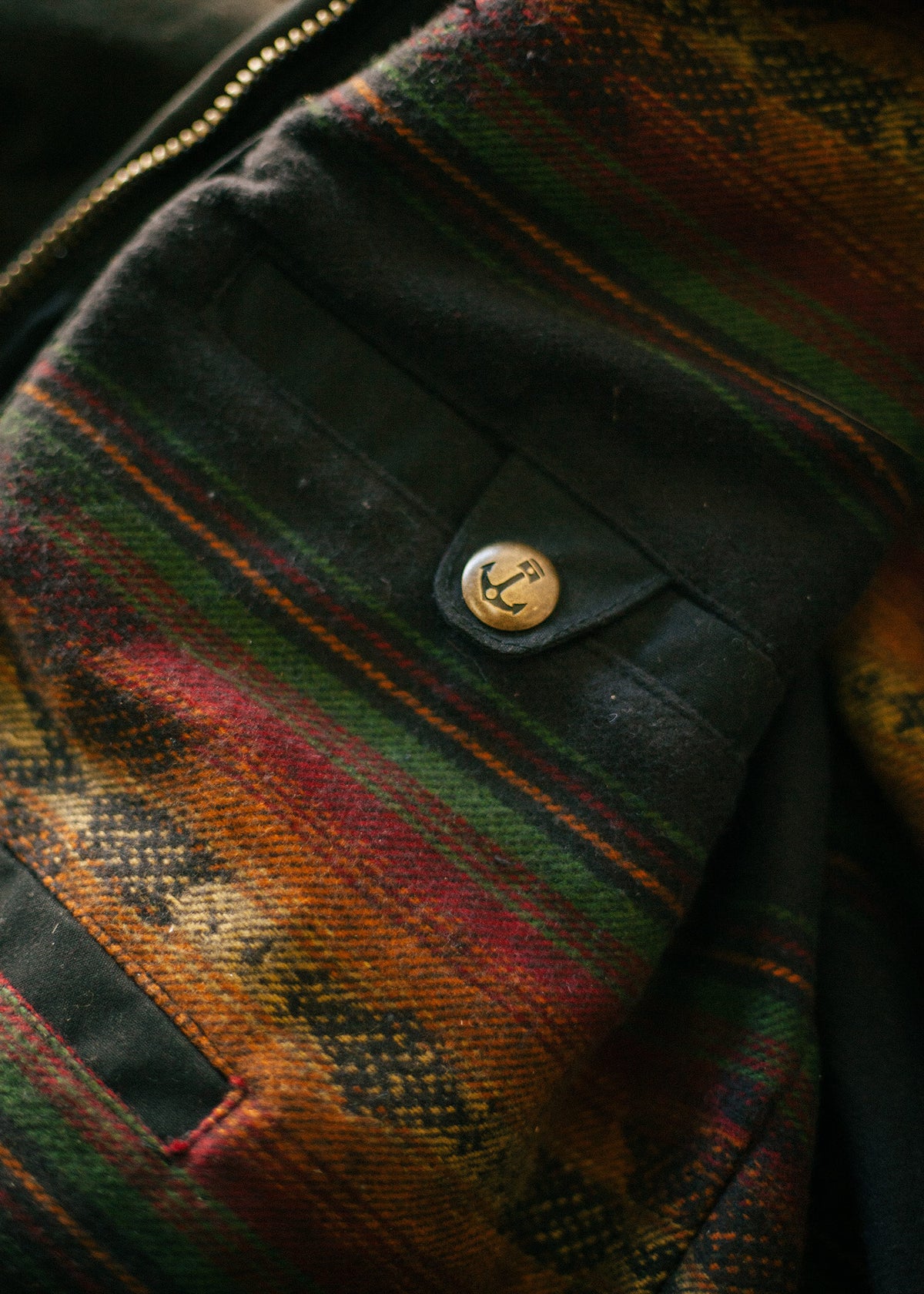 Close-up of a colorful patterned fabric with a metal button featuring an anchor design, highlighting texture and detail.