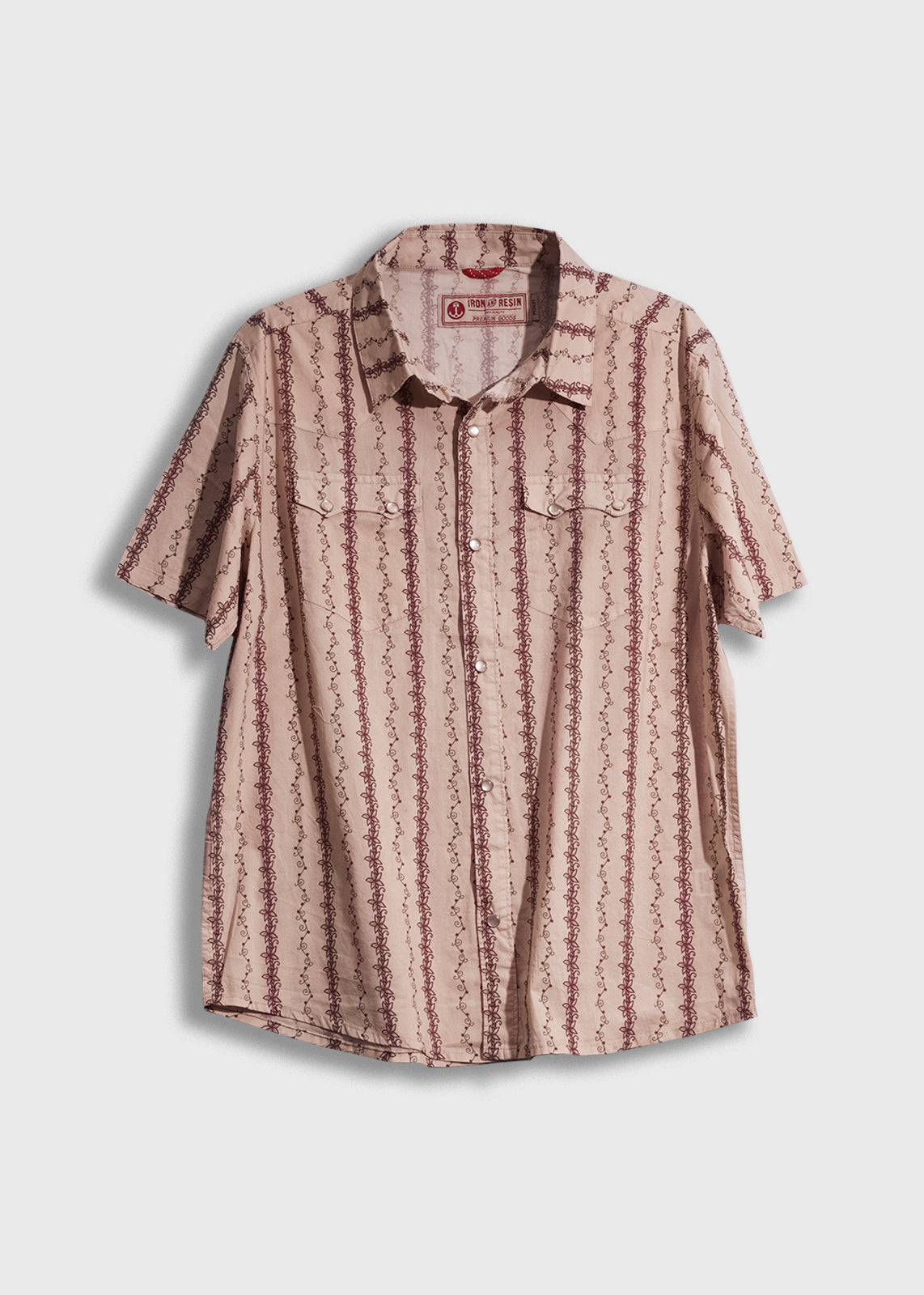 Short-sleeve beige shirt with red vertical patterns, button-up front, and two chest pockets, displayed against a white background.