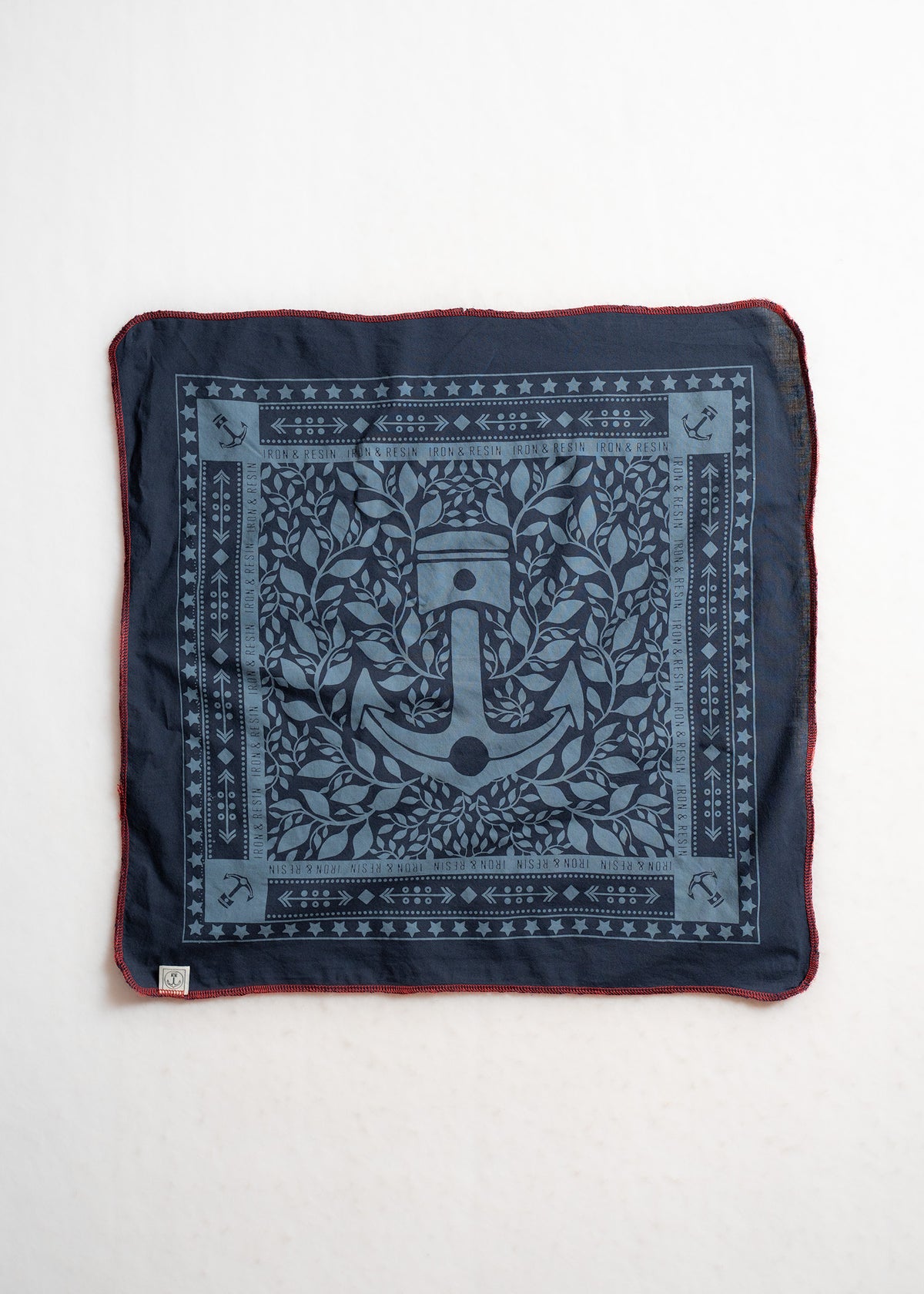 Navy bandana with anchor and leaf design, bordered by stars and arrows. Red stitching edges. Iron & Resin branding visible.
