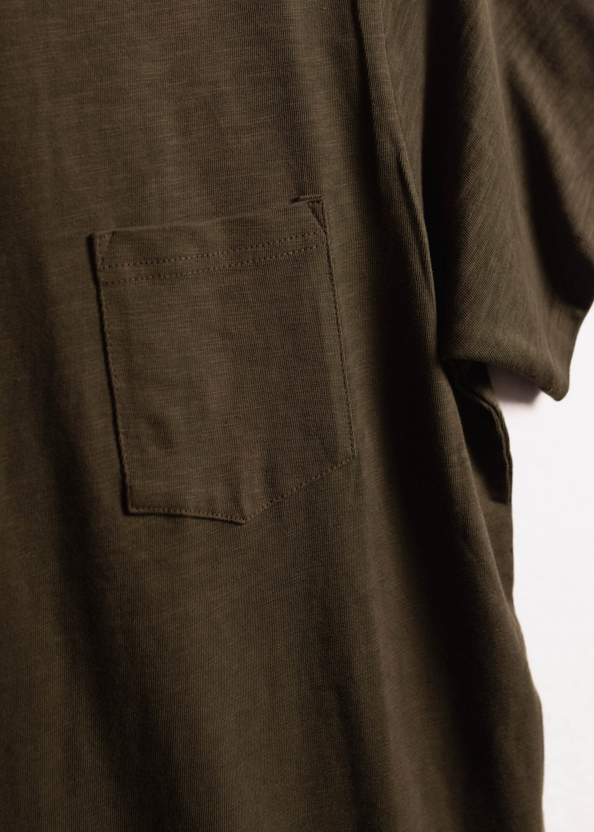 Close up of garment dyed cotton slub shirt showing chest pocket detail and textured fabric with relaxed workwear finish