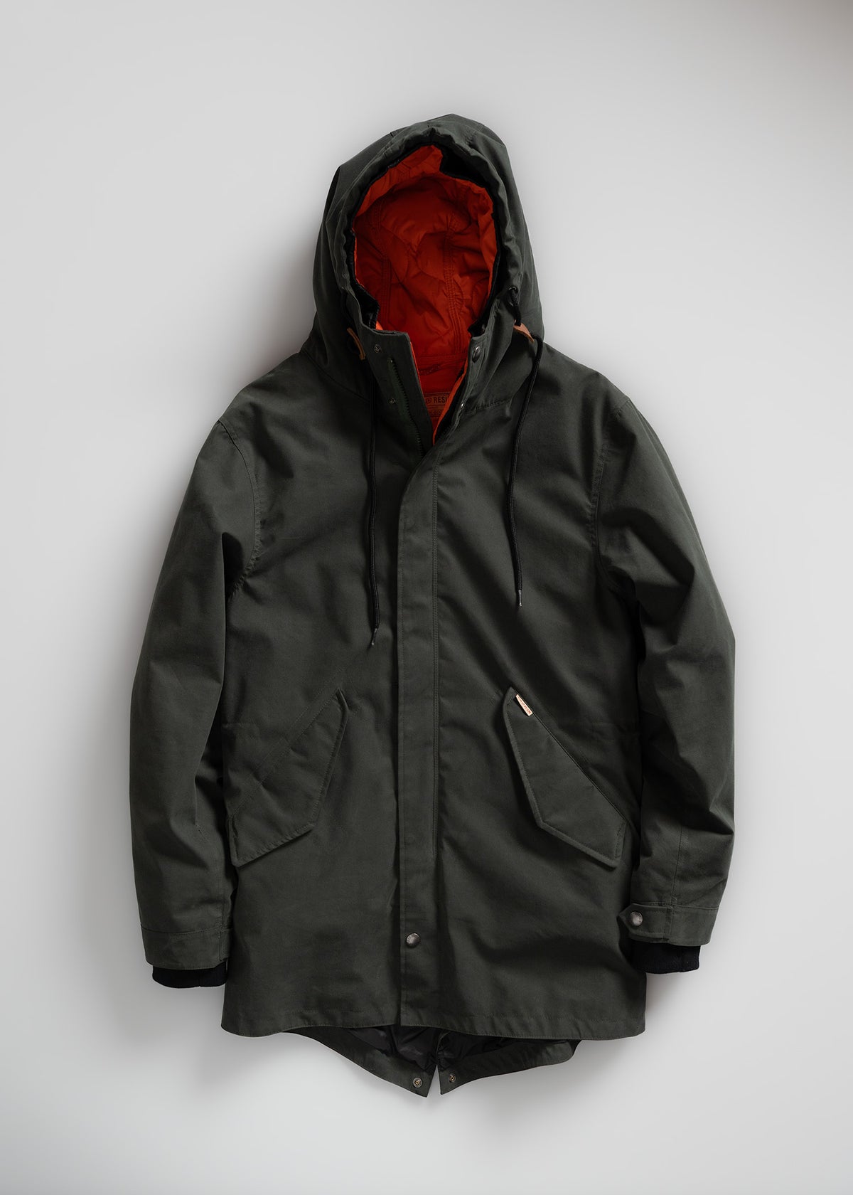 Dark green hooded jacket with orange lining, featuring large front pockets and drawstrings, displayed on a plain white background.
