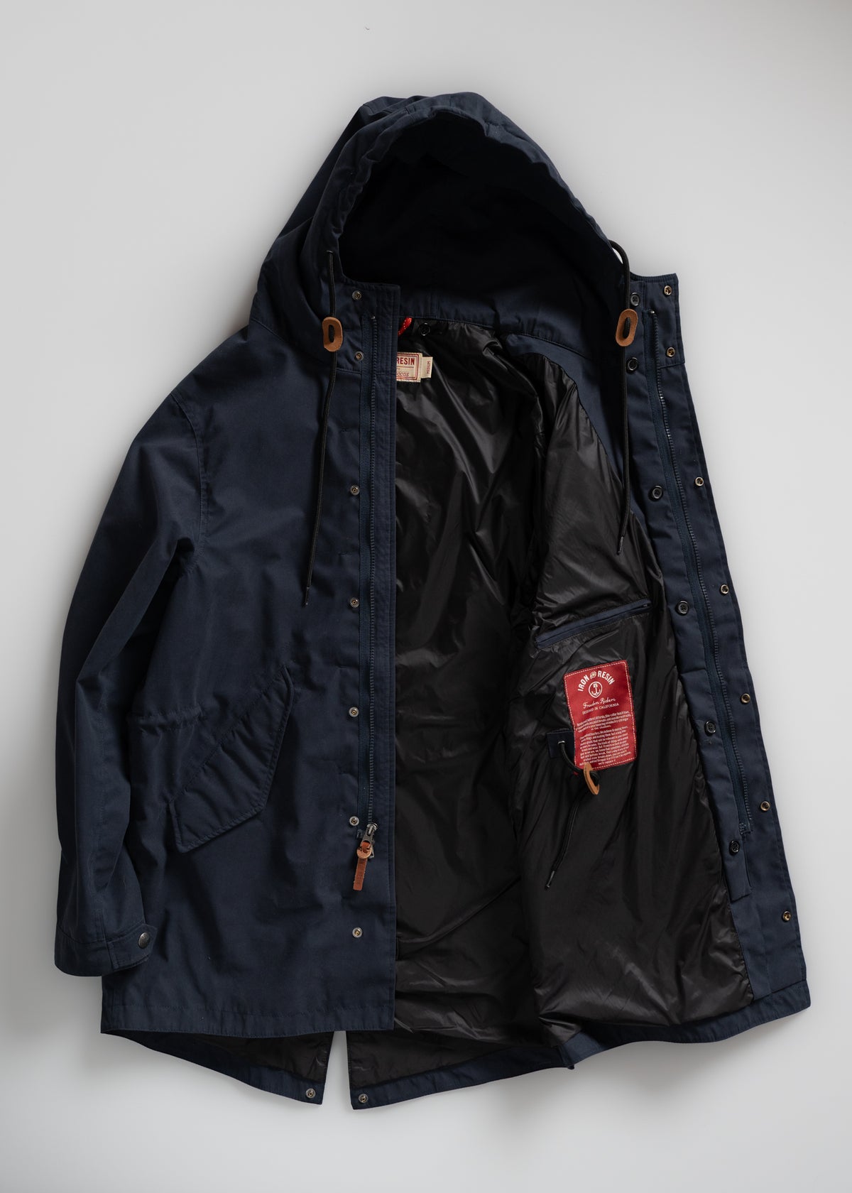 Navy hooded jacket with open front, revealing black lining and red label inside. Features wooden toggles and button details.