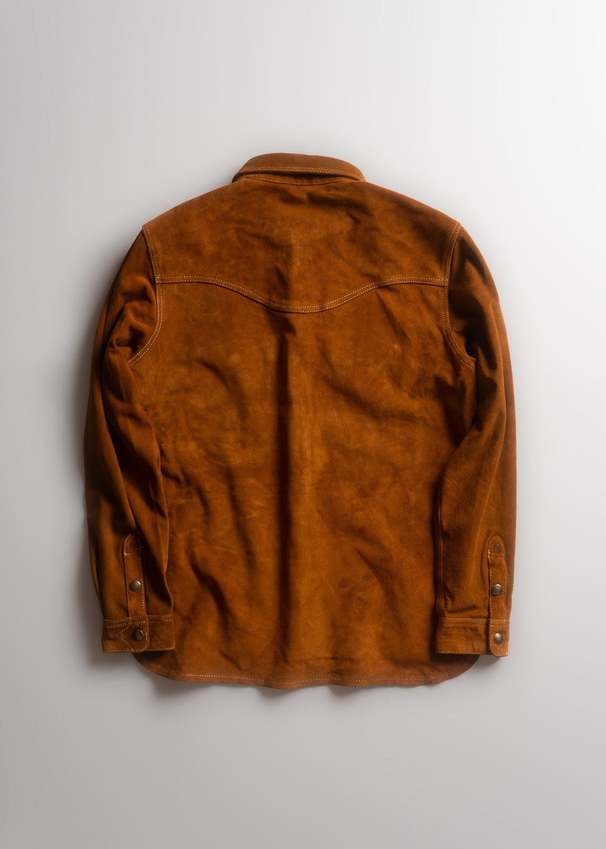 Brown suede jacket with buttoned cuffs and western-style yoke, laid flat on a light background, showcasing its back design.