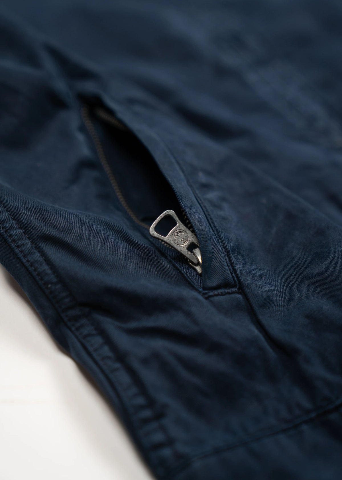 Close-up of a navy blue fabric with a partially open zipper, highlighting the texture and stitching details.