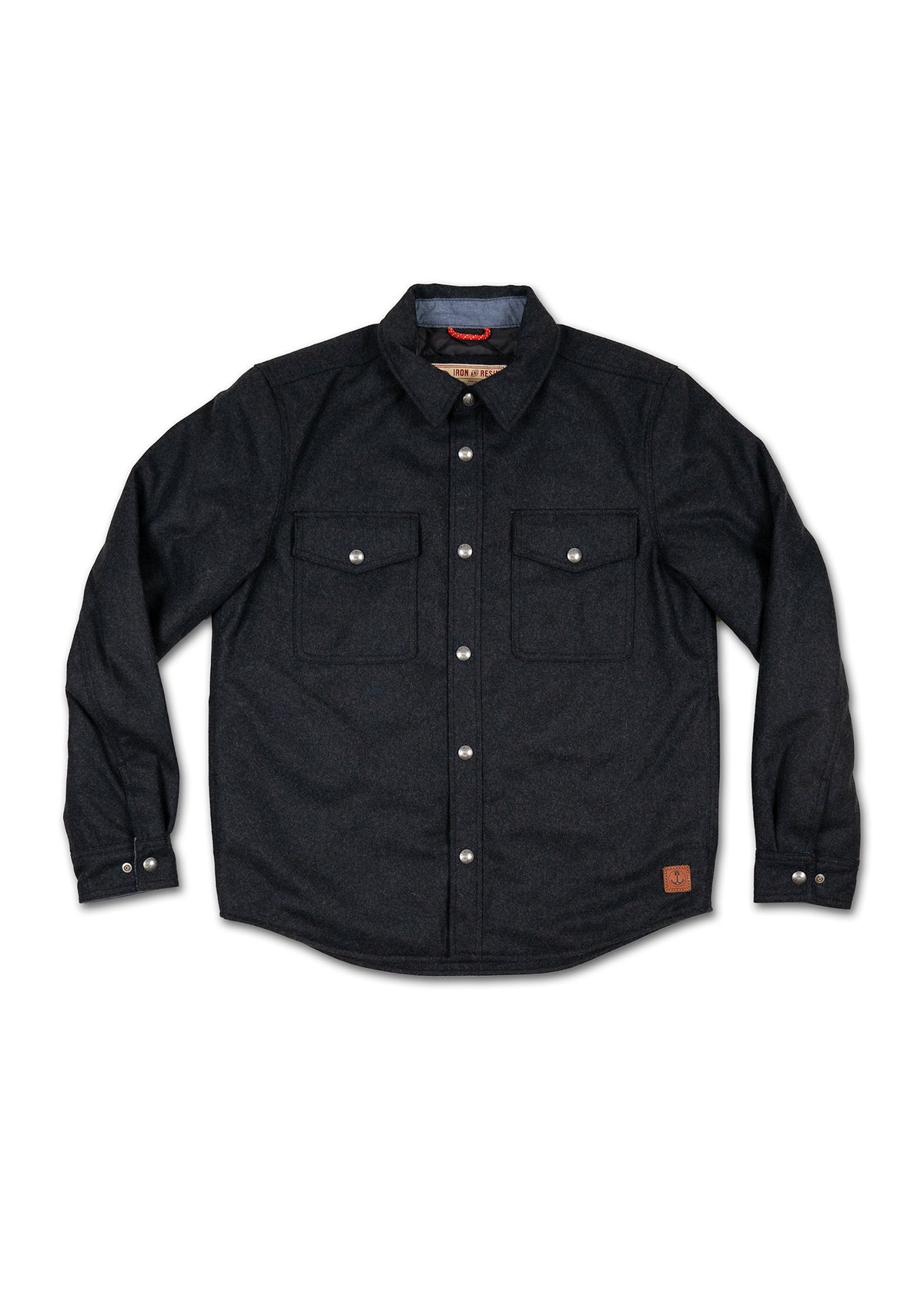 Dark button-up shirt with two chest pockets, silver buttons, and a small leather patch on the lower side, laid flat on white.