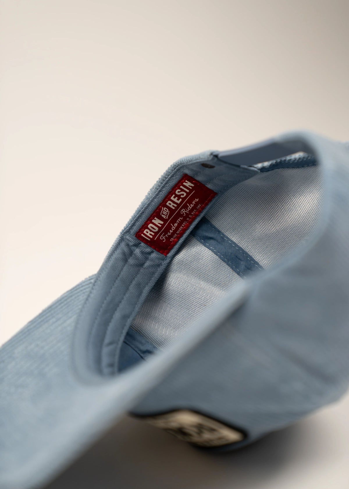 Light blue cap with a red "Iron and Resin" label inside, showcasing brand detail against a neutral background.