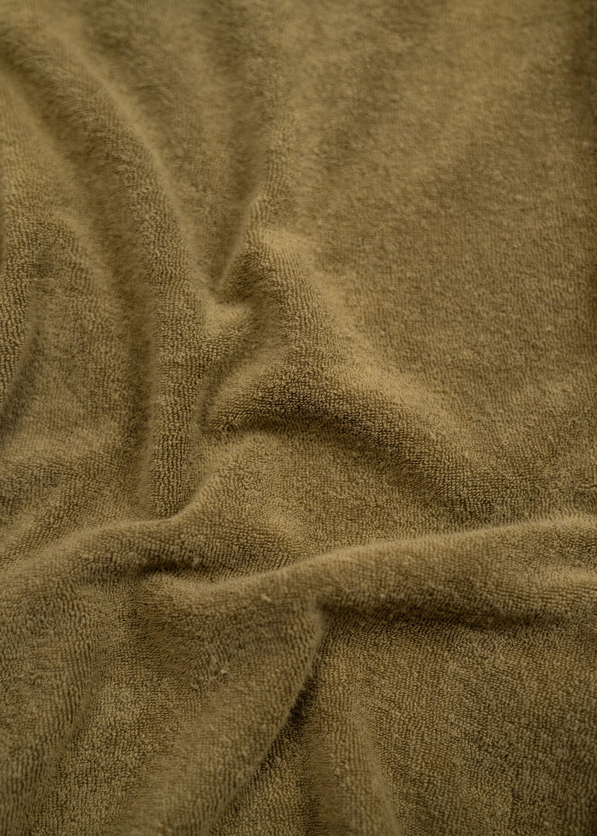 Close-up of a soft, textured brown fabric with gentle folds and shadows, creating a warm and cozy appearance.