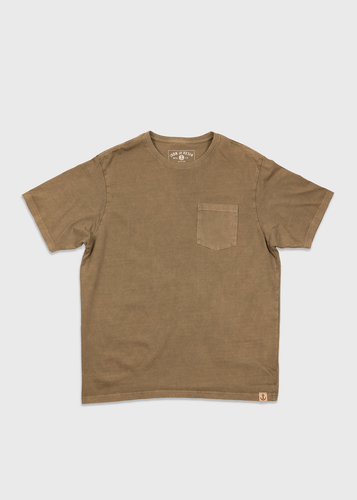 Brown T-shirt with a chest pocket on a white background. Simple design, short sleeves, crew neck, and small logo tag at the hem.