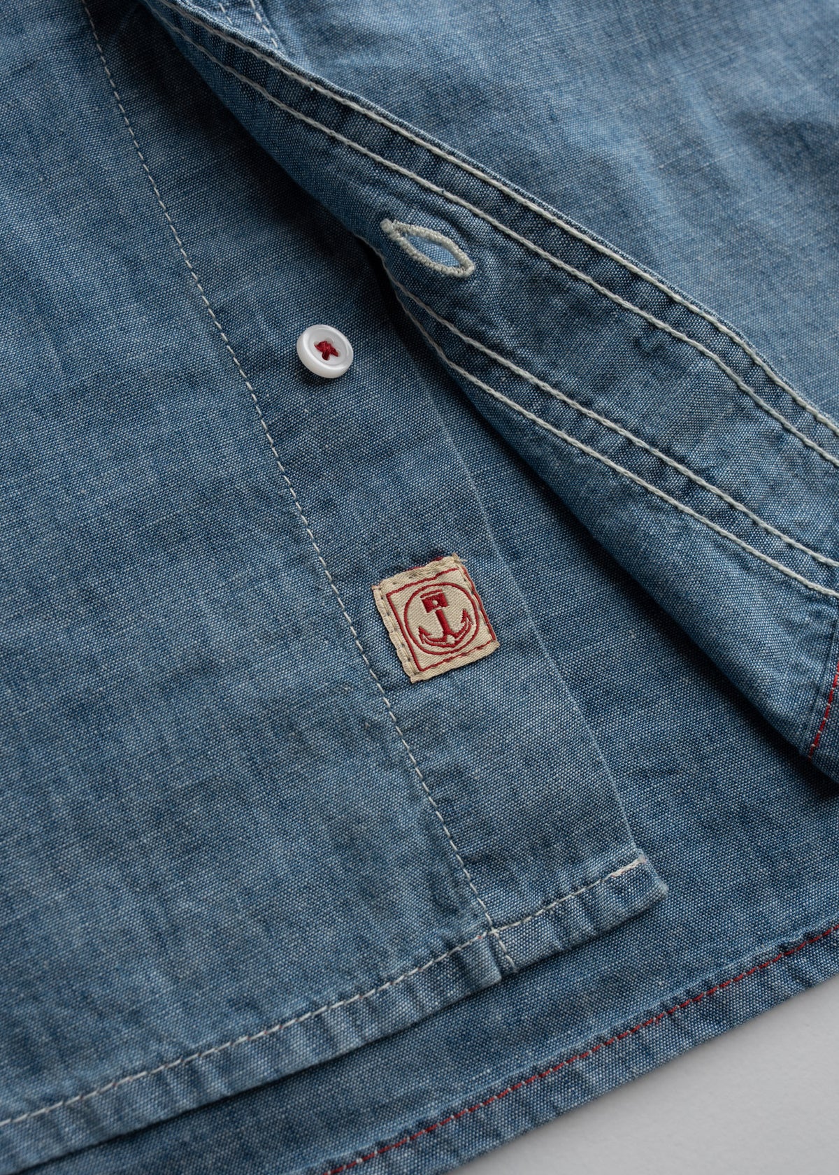 Close up of plain weave cotton fabric showing buttons, custom label, lightweight texture and breathable construction