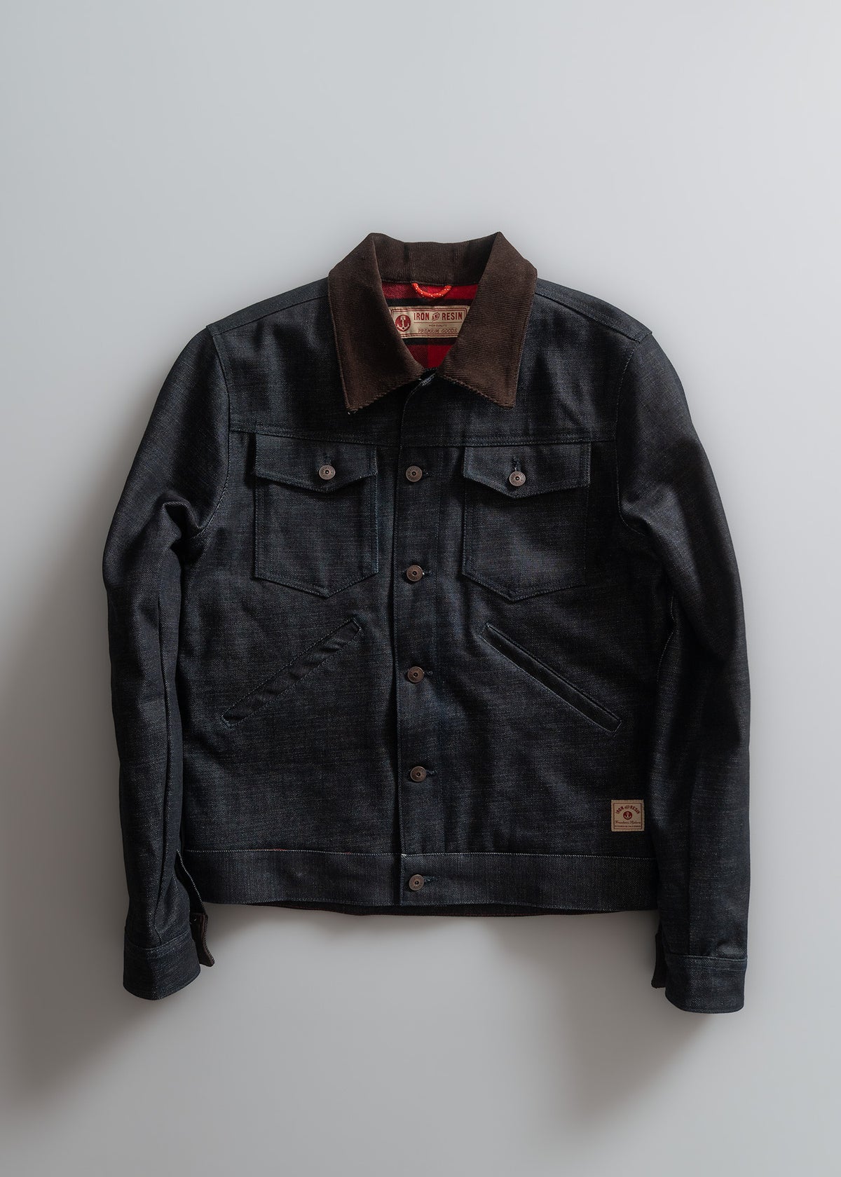Dark denim jacket with brown collar, buttoned front, and dual chest pockets, displayed against a light background.