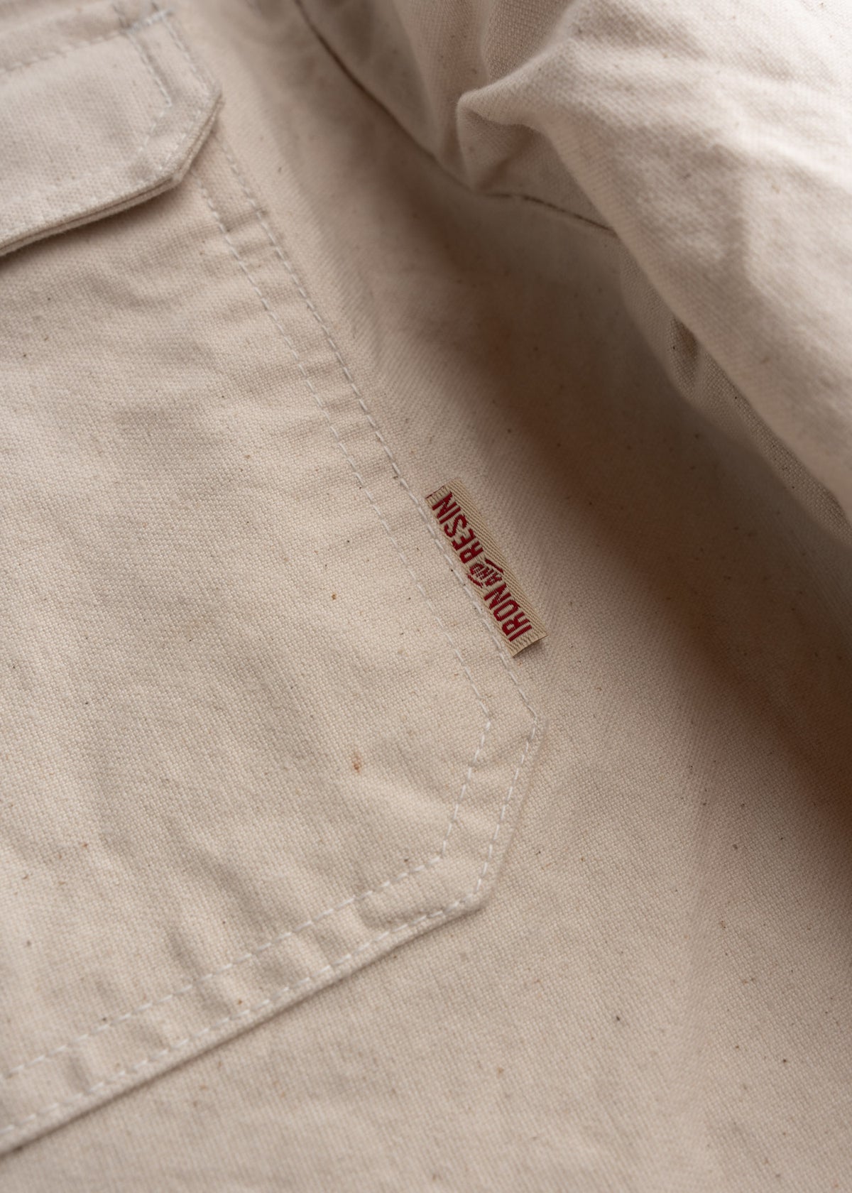 Close up of cotton canvas fabric showing, custom tag, durable weave and rugged workwear texture