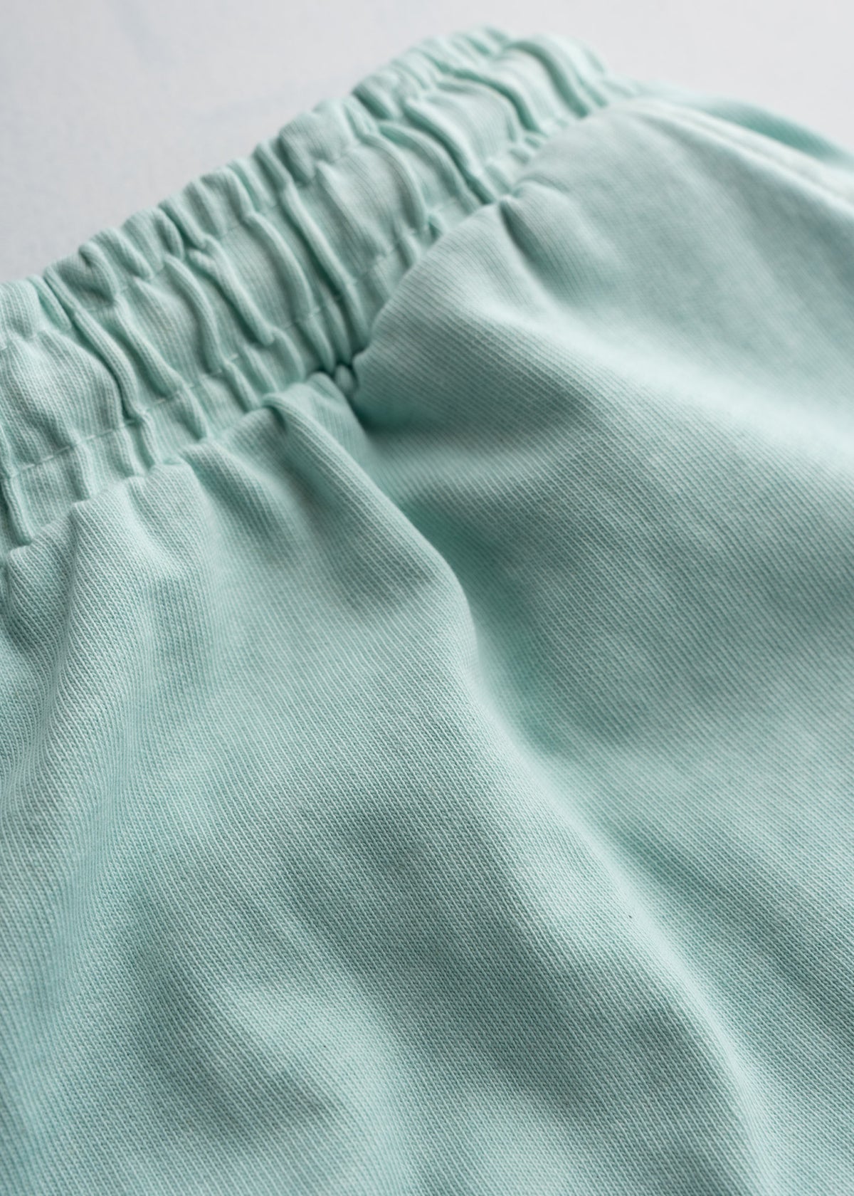 Men’s 9.5 oz jersey cotton shorts in light Blue, with drawstring waist, close-up shot showcasing fabric detail