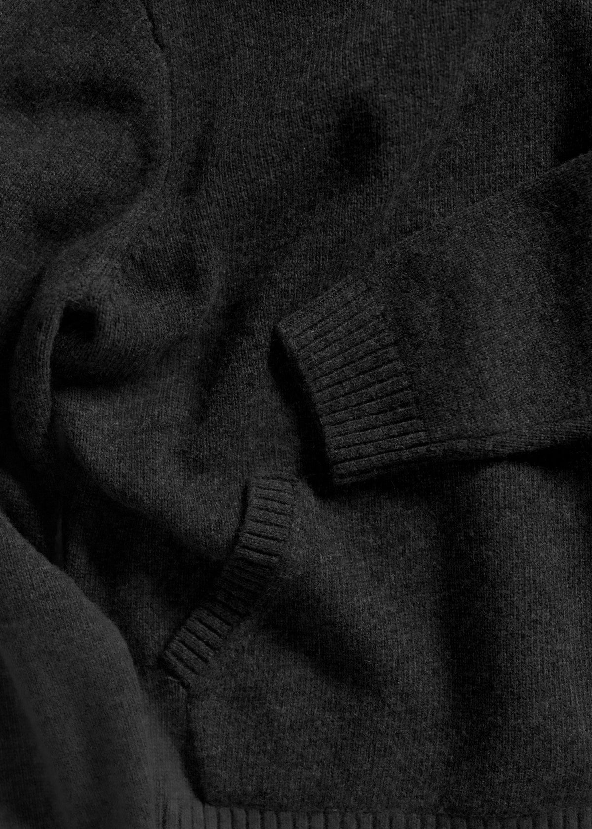 Dark wool sweater with ribbed cuffs and hem, showcasing soft texture and cozy warmth. Perfect for chilly weather comfort.