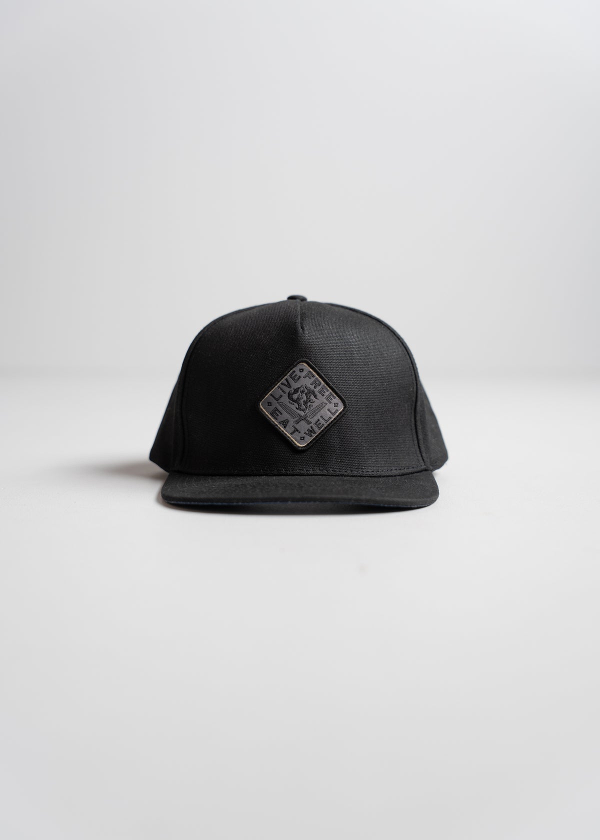 Black baseball cap with a square patch on the front, featuring a subtle design. Simple, minimalist style on a plain background.