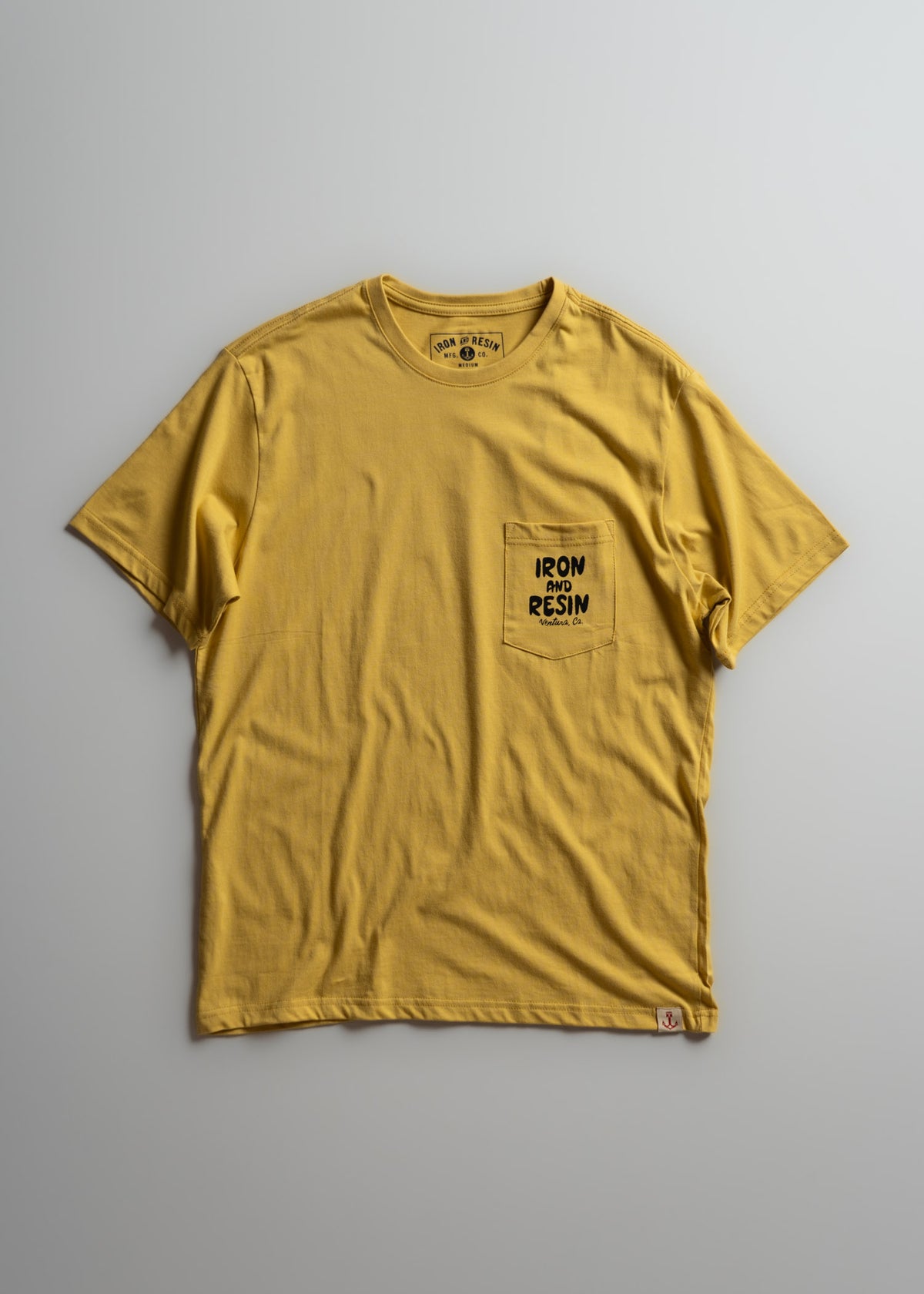 Yellow T-shirt with "Iron and Resin" logo on chest pocket, displayed on a gray background. Simple, casual design.