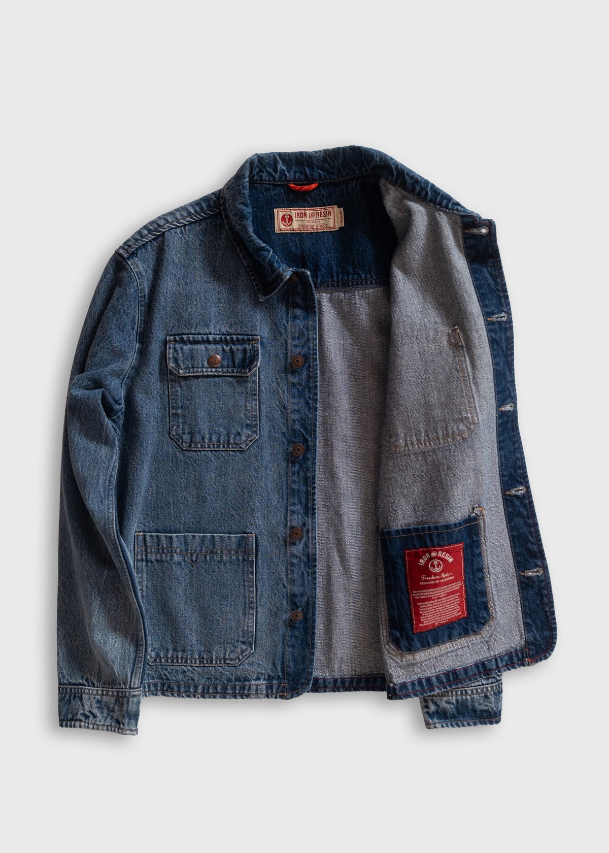 Denim jacket with open front, showing gray lining and red label. Features two chest pockets and button closure.