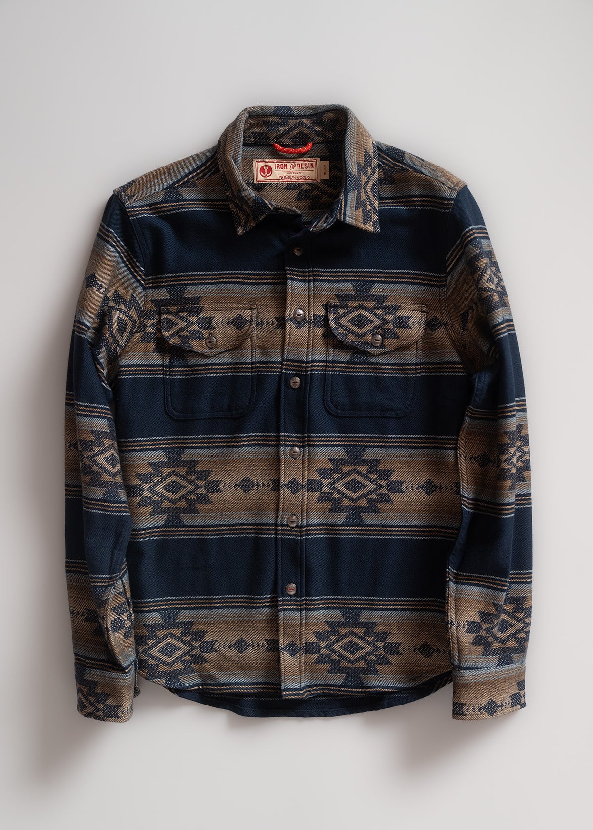 Blue and brown patterned button-up shirt with geometric designs, featuring two chest pockets, laid flat on a white background.