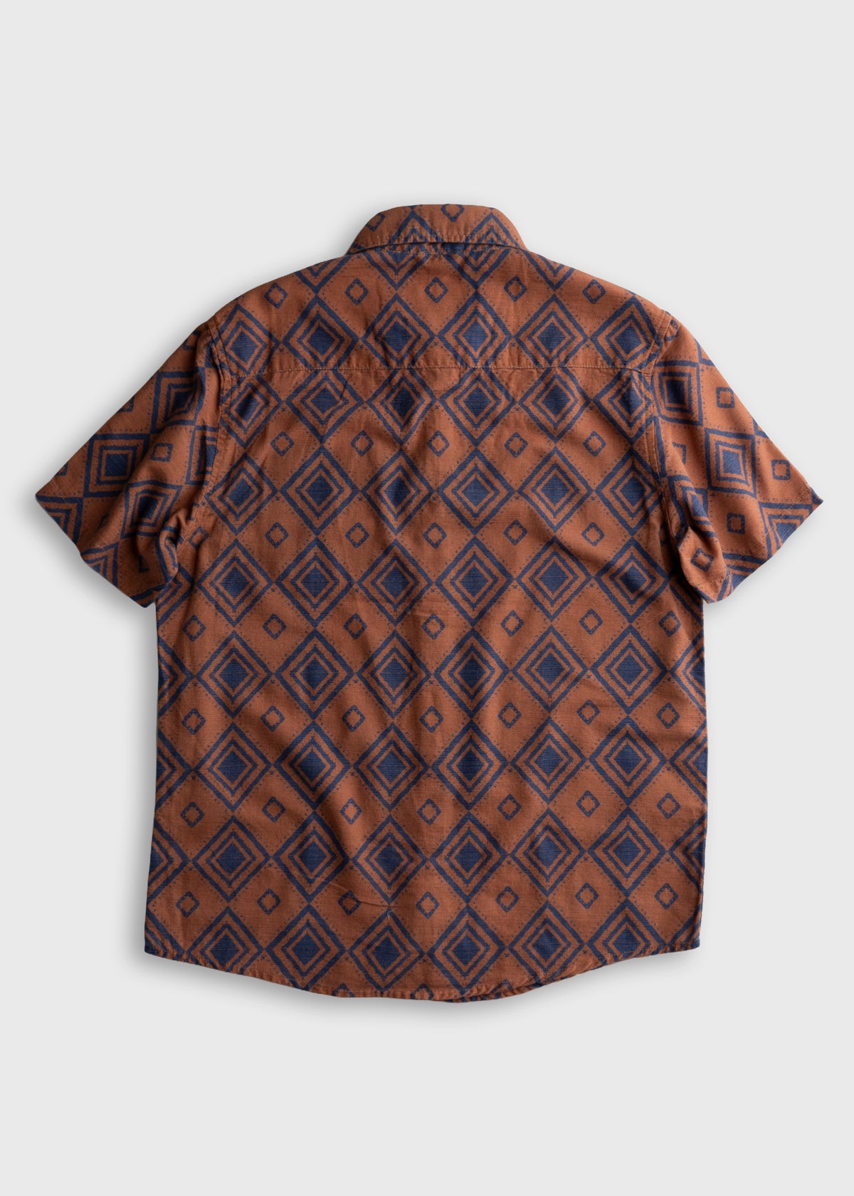 Brown short-sleeve shirt with blue diamond pattern, laid flat on a white background, showcasing its geometric design.