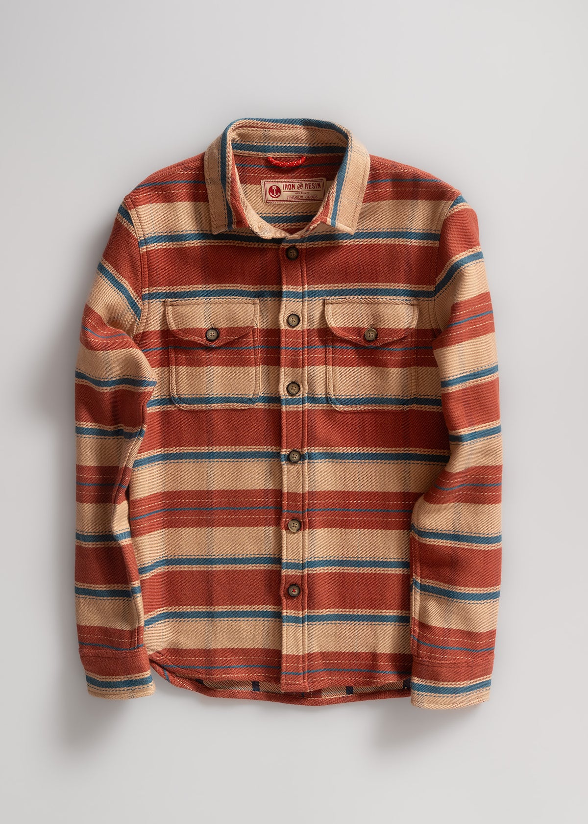 Striped flannel shirt in red, beige, and blue with button front and two chest pockets, laid flat on a light background.