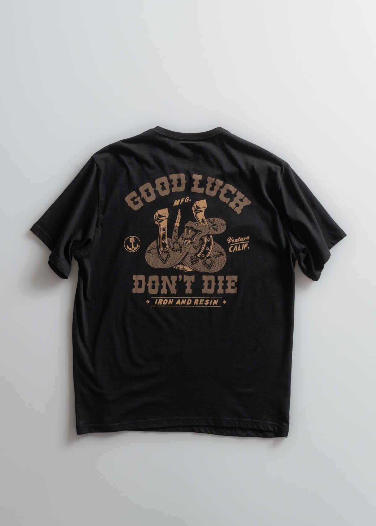 Black t-shirt with "Good Luck Don't Die" and snake design in brown. Text includes "Iron and Resin" and "Ventura Calif."