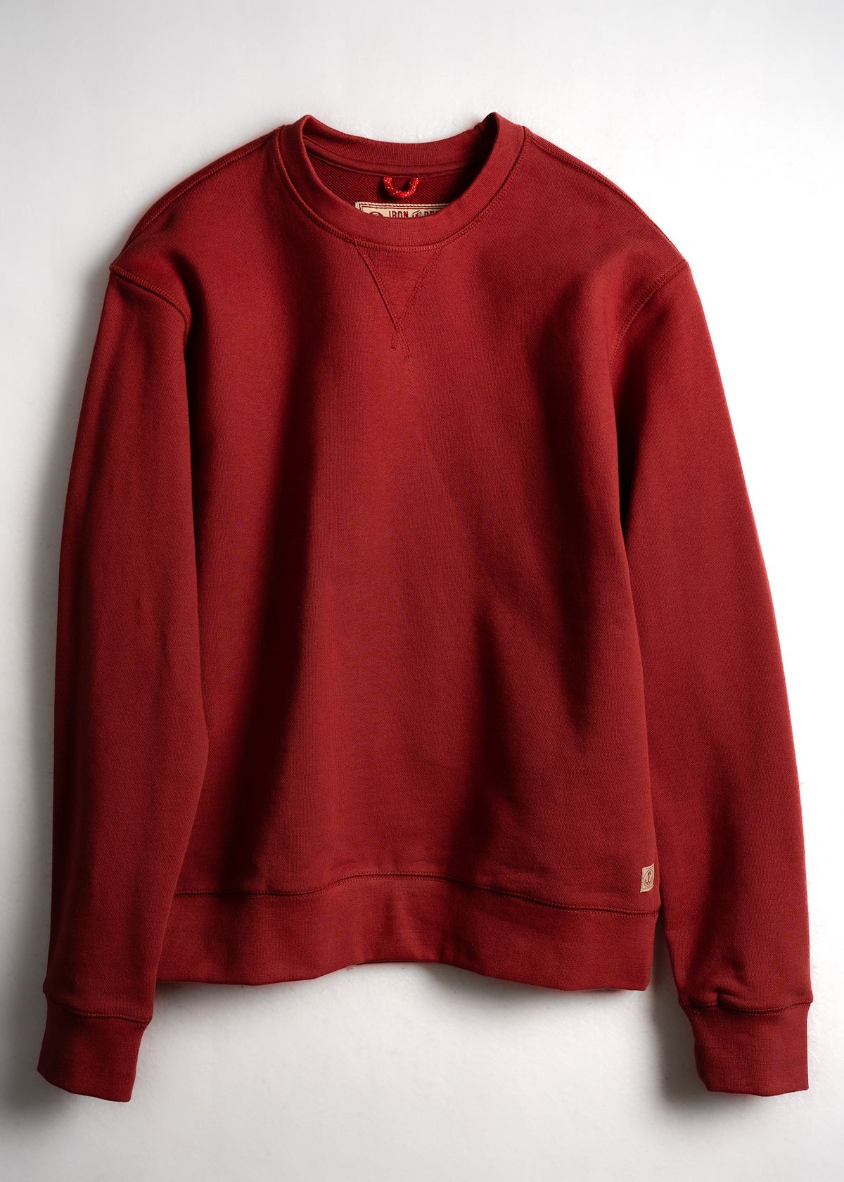 Red crewneck sweatshirt with ribbed cuffs and hem, displayed against a white background. Simple, classic design.
