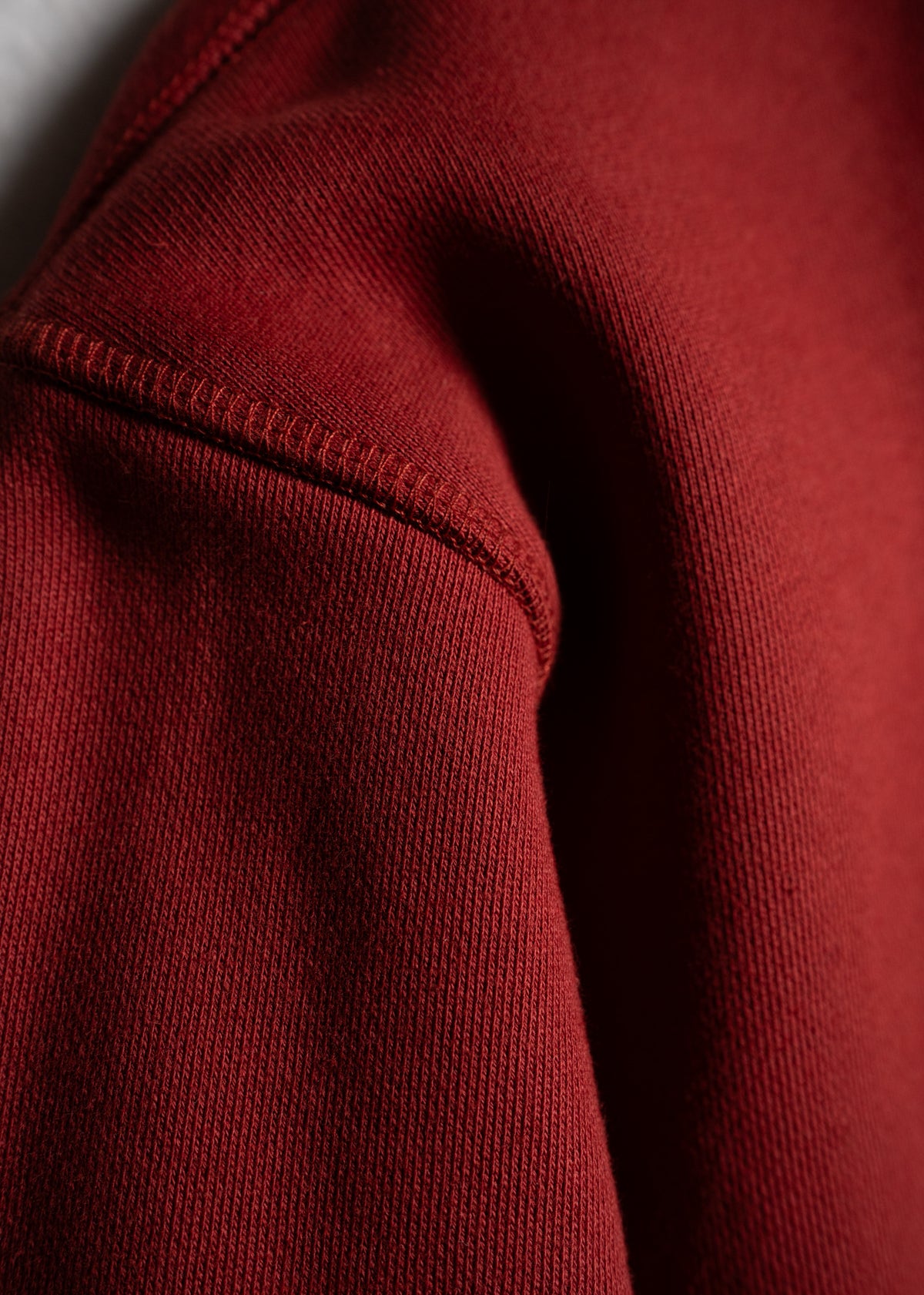 Close-up of a red sweatshirt fabric showing detailed stitching and texture, highlighting the garment's quality and craftsmanship.