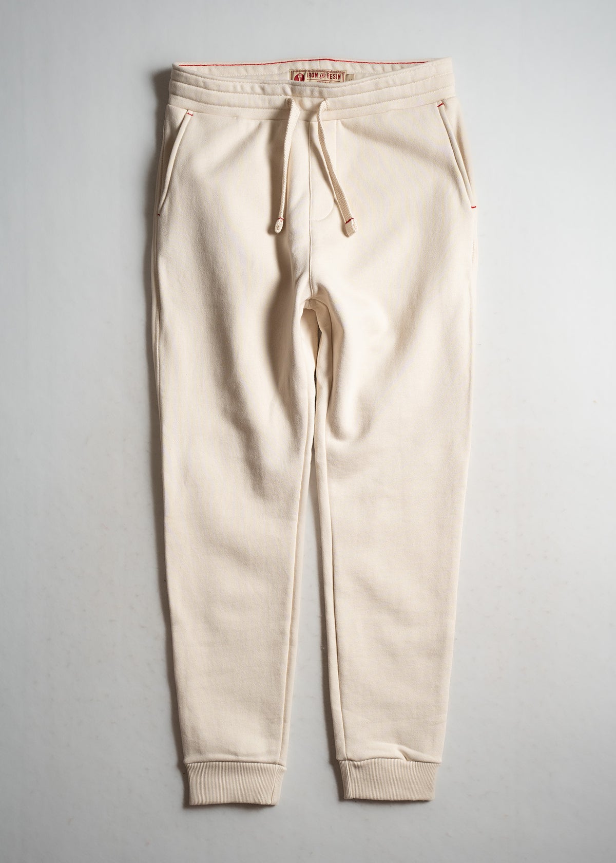 Cream jogger pants with drawstring waist and pockets, displayed flat on a light background, showcasing casual style.