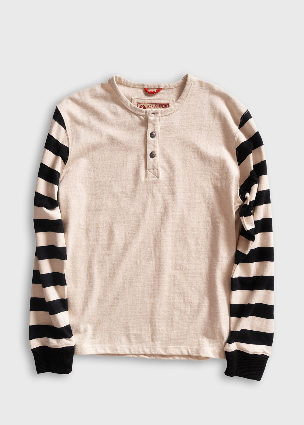 Cream henley shirt with black and white striped sleeves, featuring a three-button placket, laid flat on a white background.