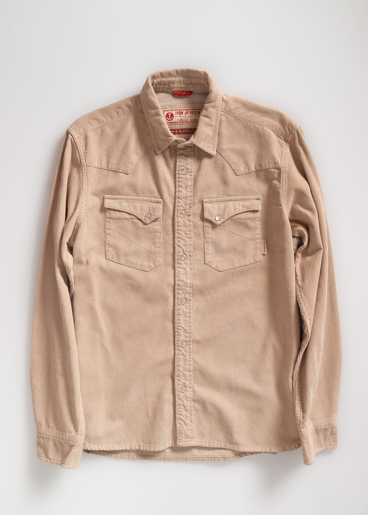 Tan corduroy shirt with buttoned front and two chest pockets, displayed against a plain background, highlighting its texture.