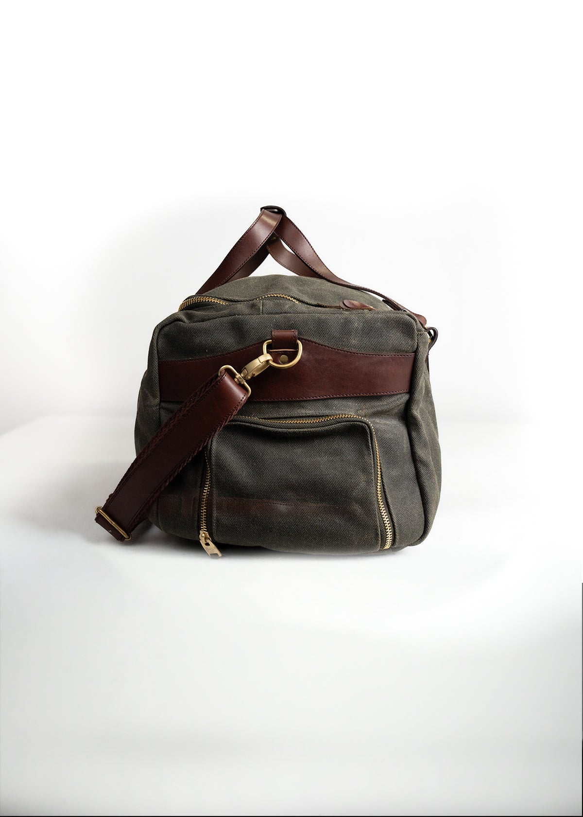 Canvas and leather bag with brown strap and gold zipper on white background, showcasing a classic, durable design for travel.