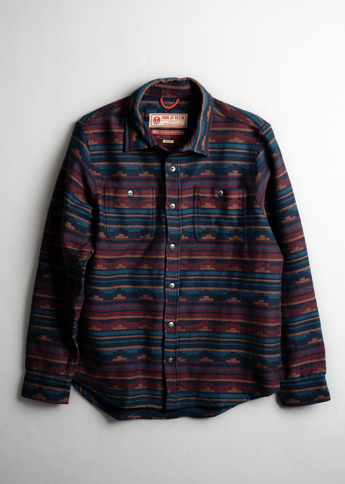 Striped button-up shirt with a geometric pattern in blue and red tones, featuring two chest pockets and a collar.