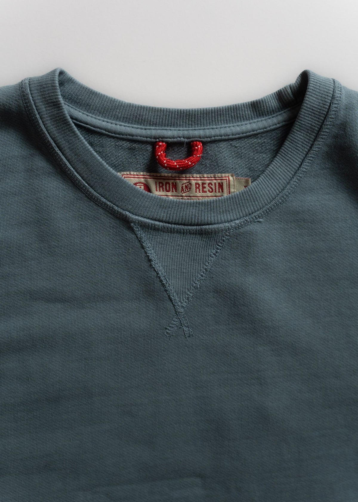 Blue sweatshirt with a red loop and "Iron and Resin" label visible inside the collar, showcasing a rugged, casual style.