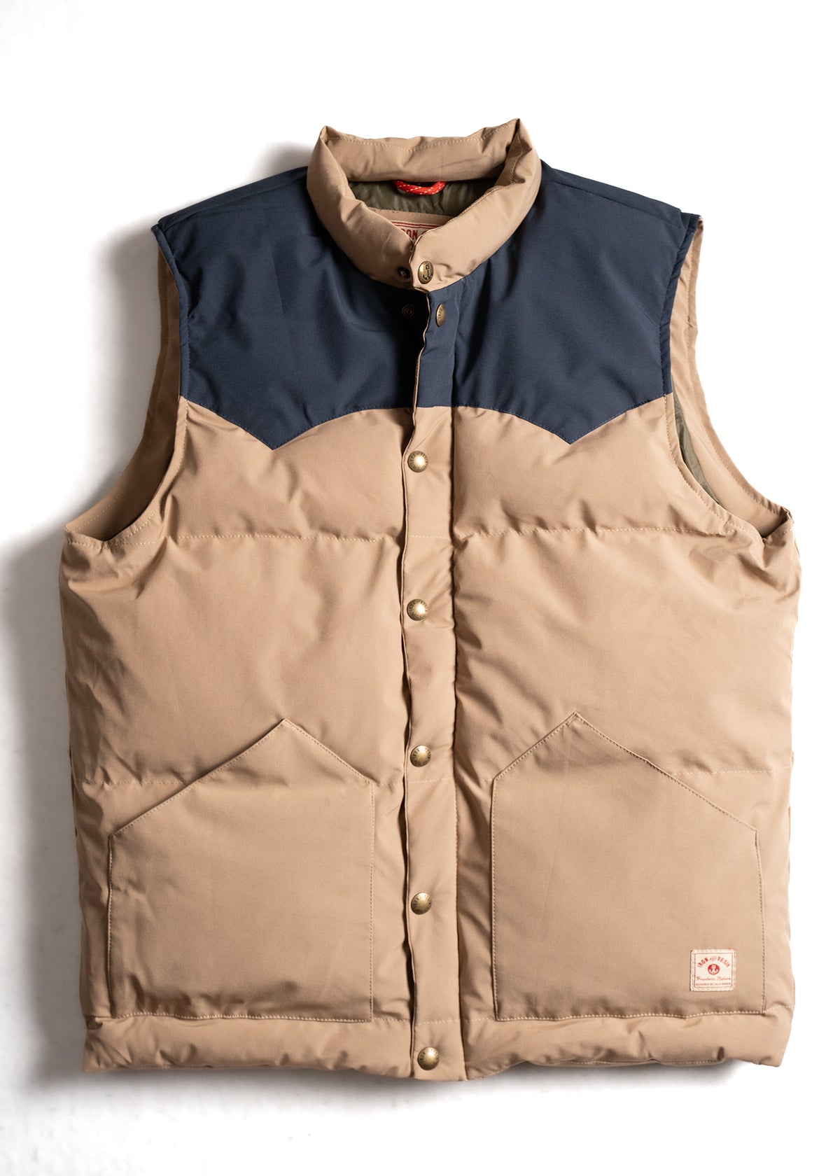 Tan and navy puffer vest with button closure and two front pockets, laid flat on a white background.
