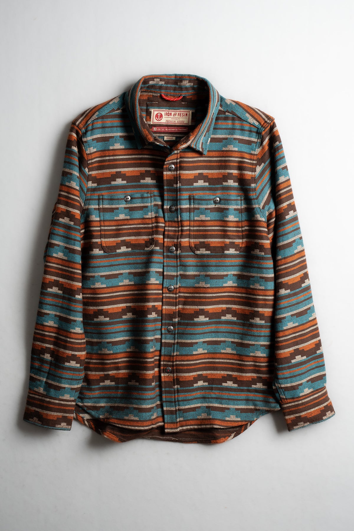 Striped flannel shirt with brown, blue, and orange patterns, featuring buttoned front and collar, displayed on a white background.