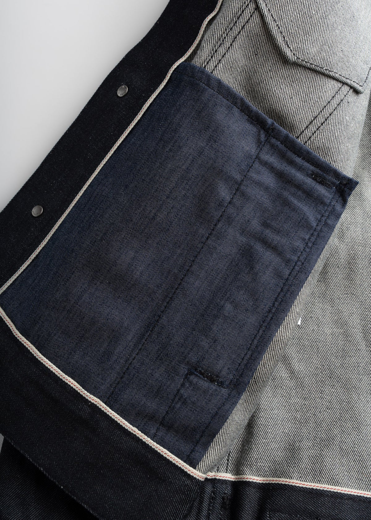 Denim jacket interior with visible stitching, dark blue pocket, and contrasting fabric lining detail.