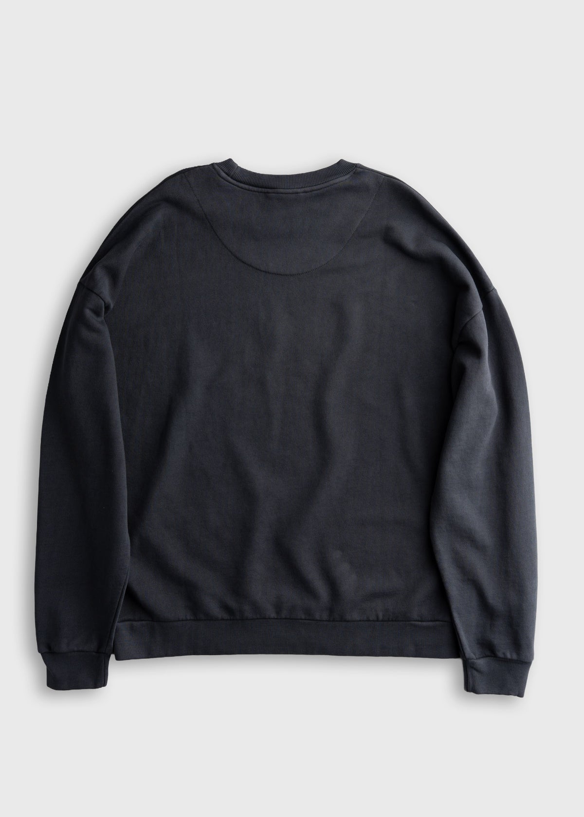Back view of a plain black sweatshirt on a light gray background, showcasing its simple design and relaxed fit.